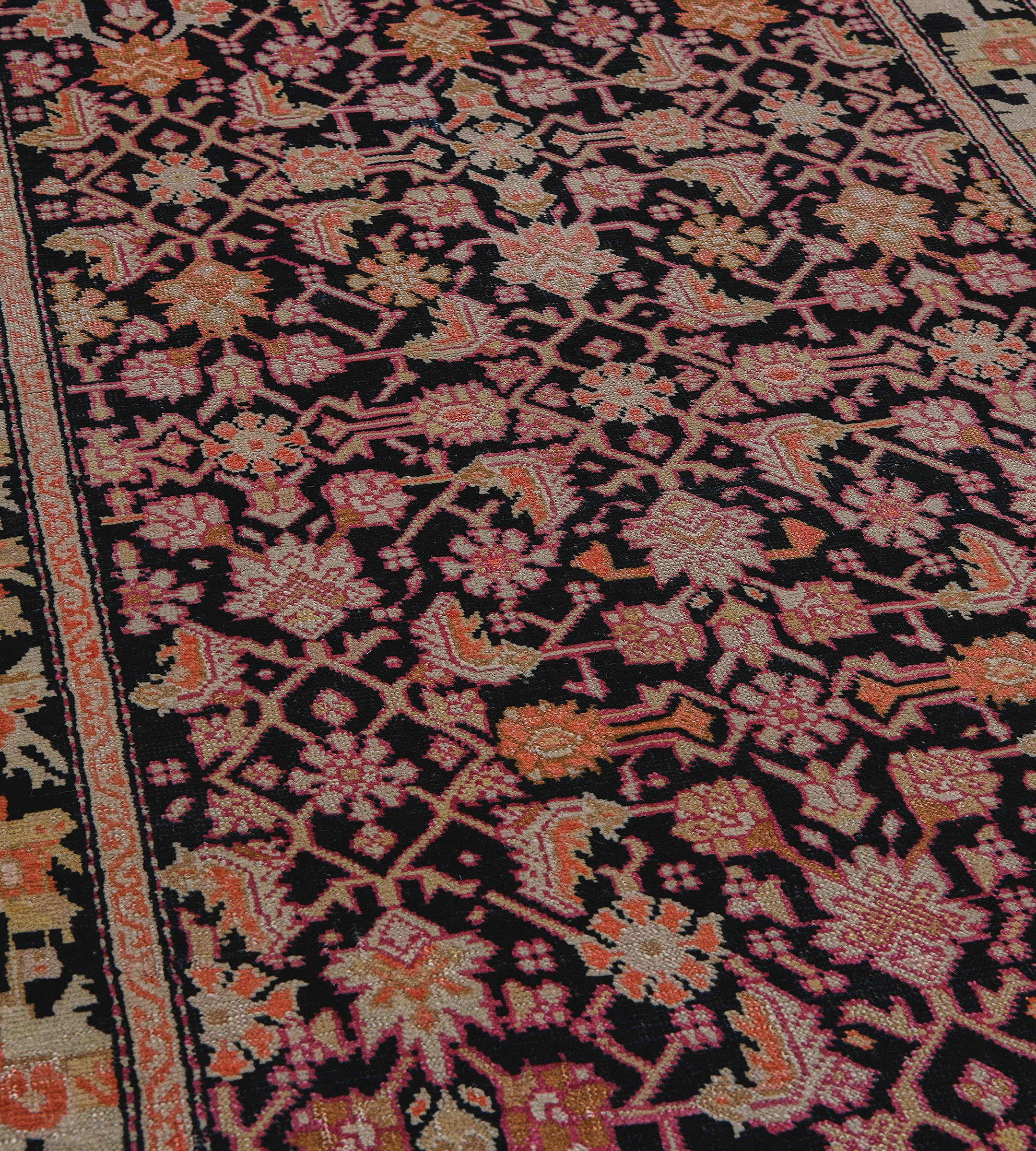 This antique, circa 1920, Karabagh runner has a charcoal-black field with an overall herati-pattern of pistachio-green, soft terracotta, sandy-yellow and shaded raspberry-red, in a charcoal-black border of pistachio-green and ivory linked angular