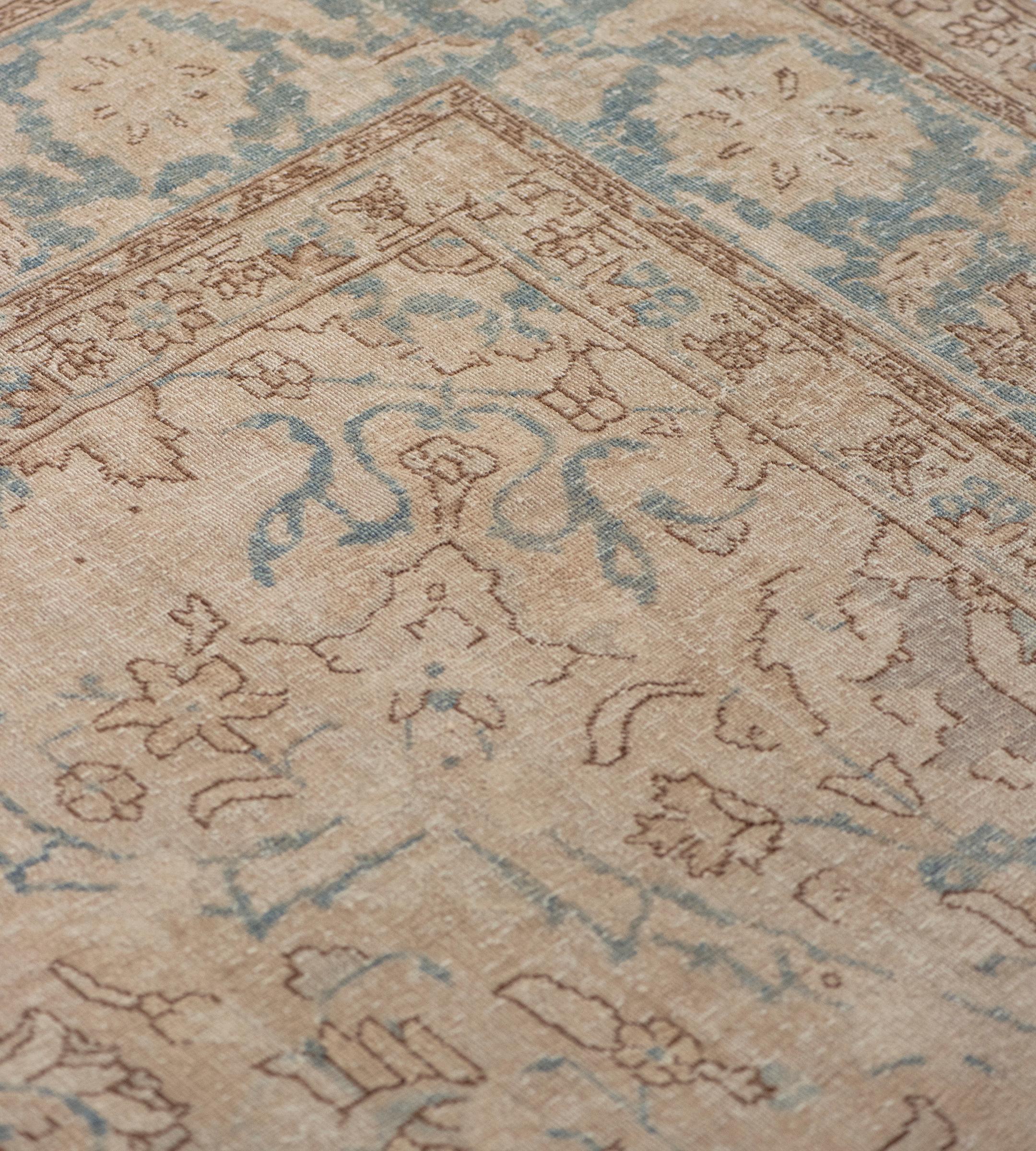 Dieser antike Teppich aus Täbriz (ca. 1920) hat ein weiches, buff-braunes Feld mit verschlungenen Blumenranken um ein zentrales, hellblaues, fettes Medaillon mit Blumenvasen-Anhängern, ein zentrales, buff-braunes Rautenmedaillon mit einem zentralen