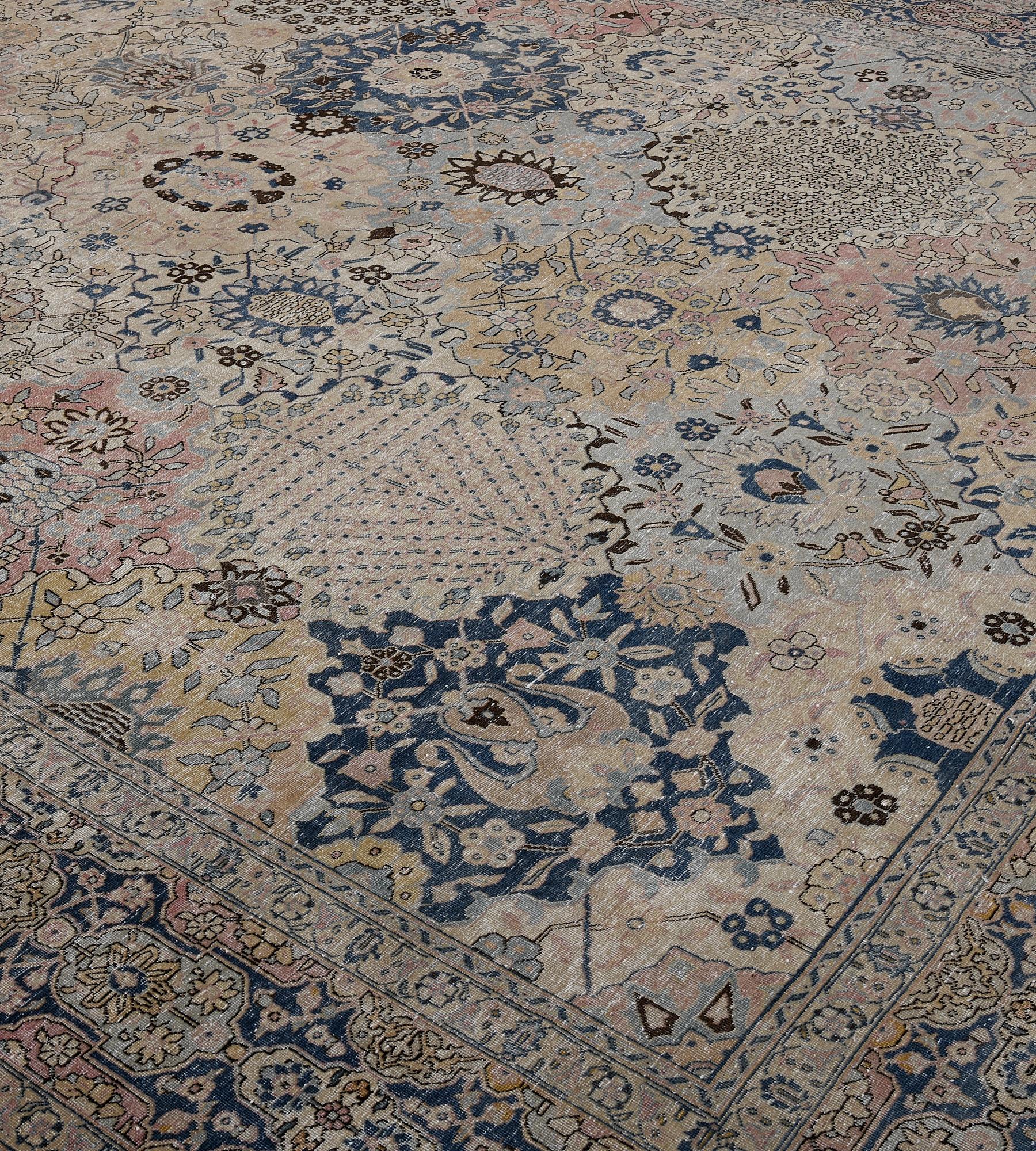 This antique, Circa 1920, Tabriz rug features a field with diagonal rows of bold polychrome cusped lozenges each containing dense floral sprays alternating with central palmettes issuing angular floral vine, in a broad indigo border with linked