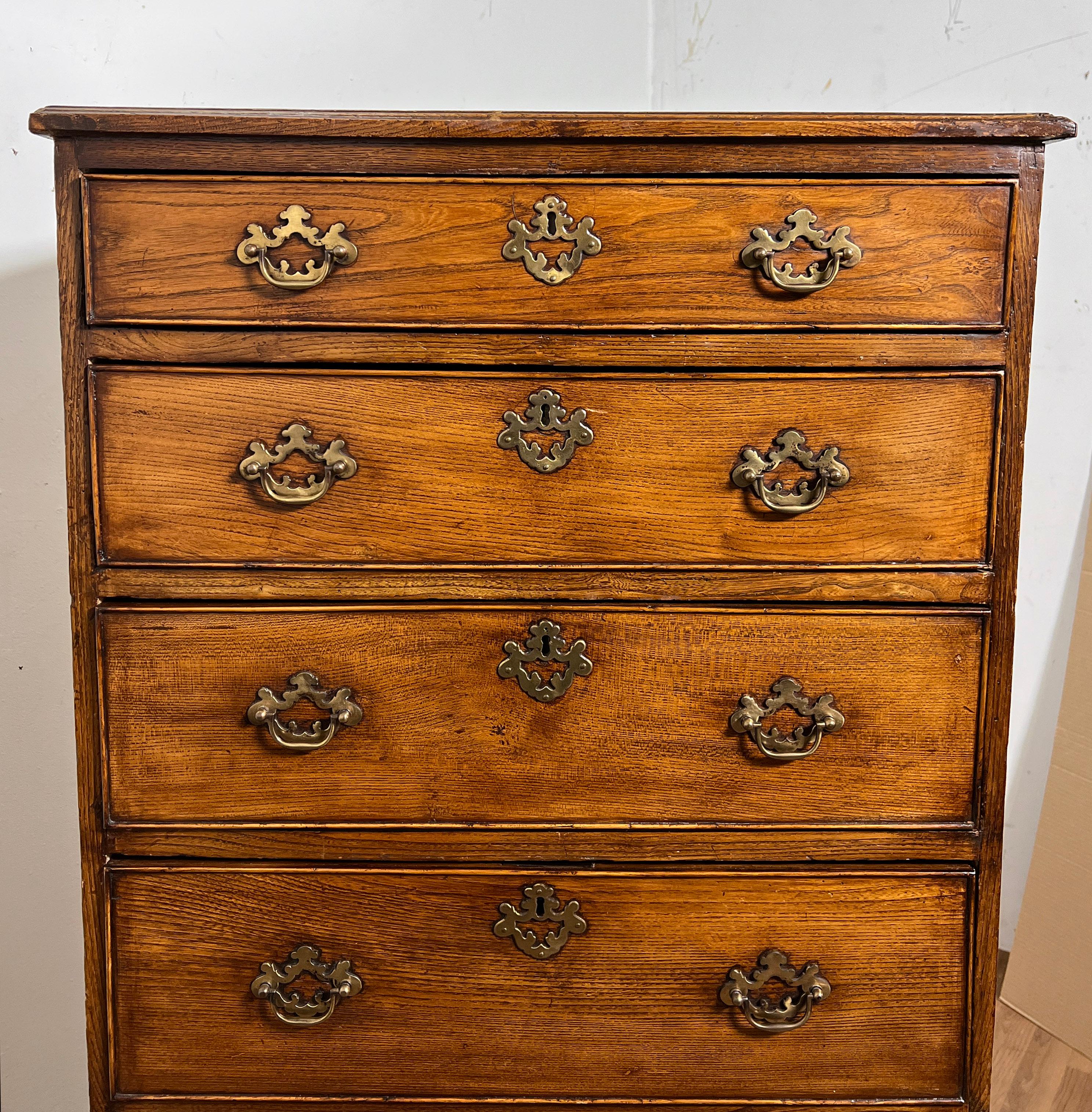  A late 1700s Georgian tall chest of six graduated drawers in oak with pierced batwing brasses and beaded drawers on high bracket feet.