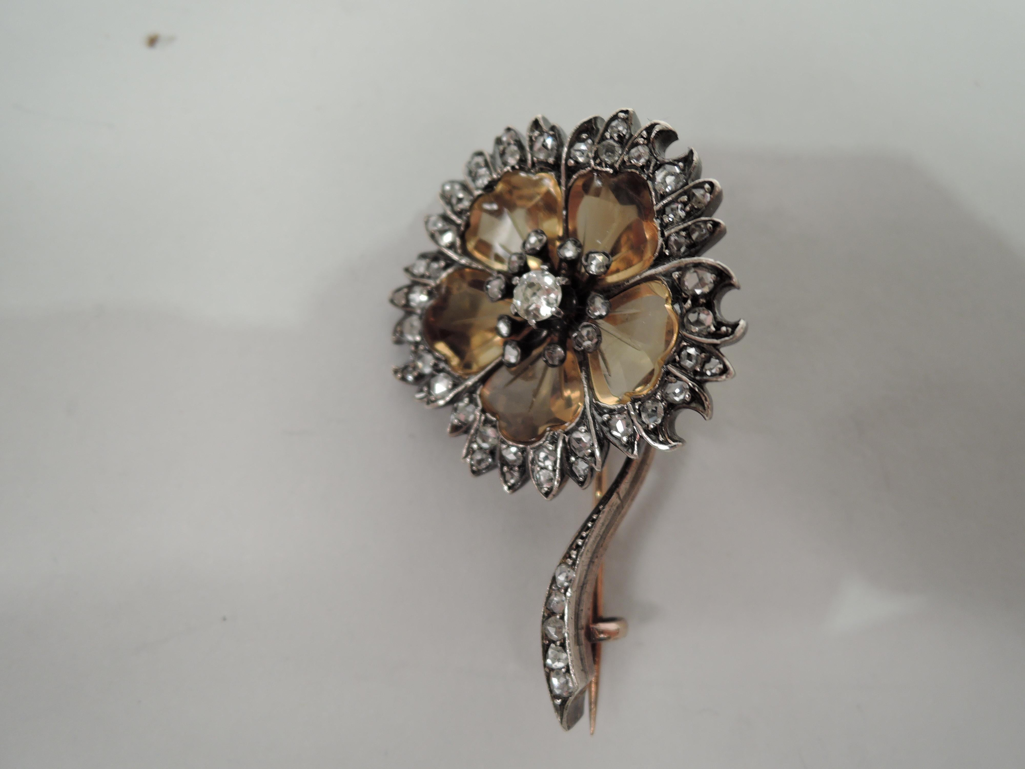 This pretty brooch with stones mounted in silver-topped 18k gold has been designed in the shape of a flower. The petals have been formed from 5 incised citrines in a warm smokey yellow-brown color which surround a cut diamond in the center. The stem