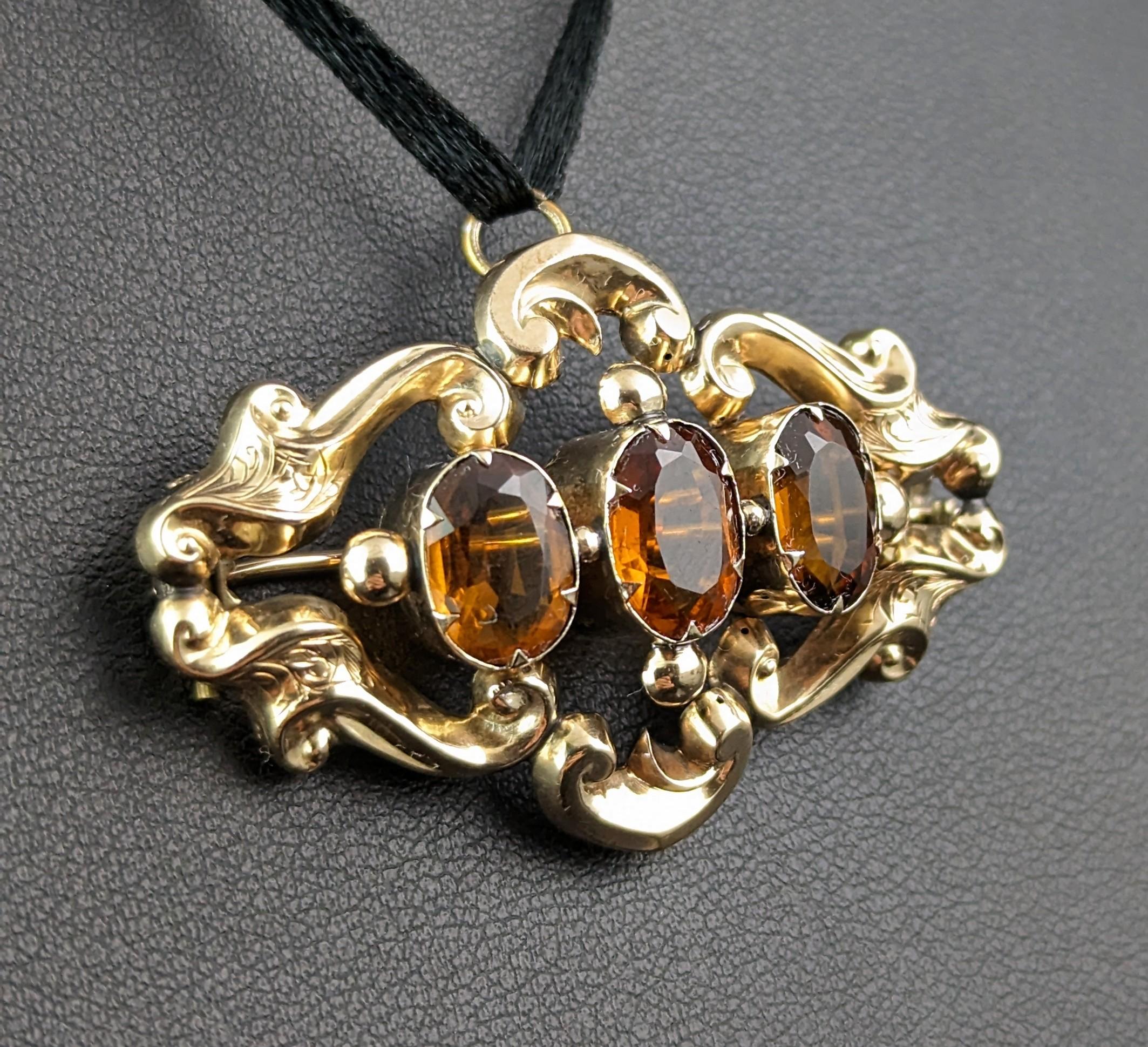 A gorgeous antique Citrine pendant brooch.

This pretty piece is designed in 9ct yellow gold with a scrollwork design in rich tones, the pendant brooch is set with three oval cut citrine's with a lovely warm cognac glow.

The brooch fastens with an
