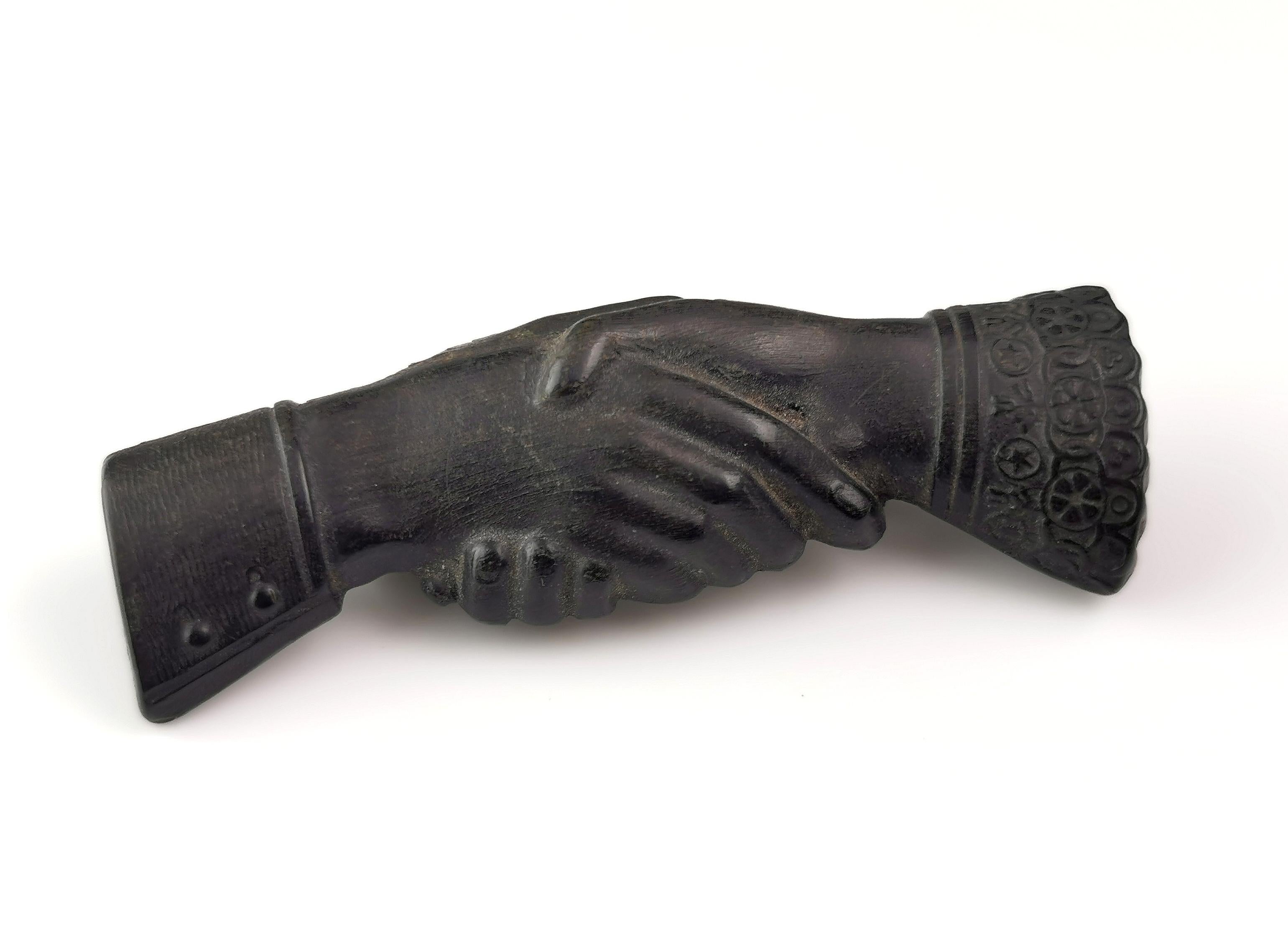 An interesting and scarce Victorian clasped or shaking hands brooch.

It is crafted from bog oak with a rich deep brown / black colour.

The pin is carved as two hands clasped or shaking not dissimilar to the earlier Fede style often found in rings
