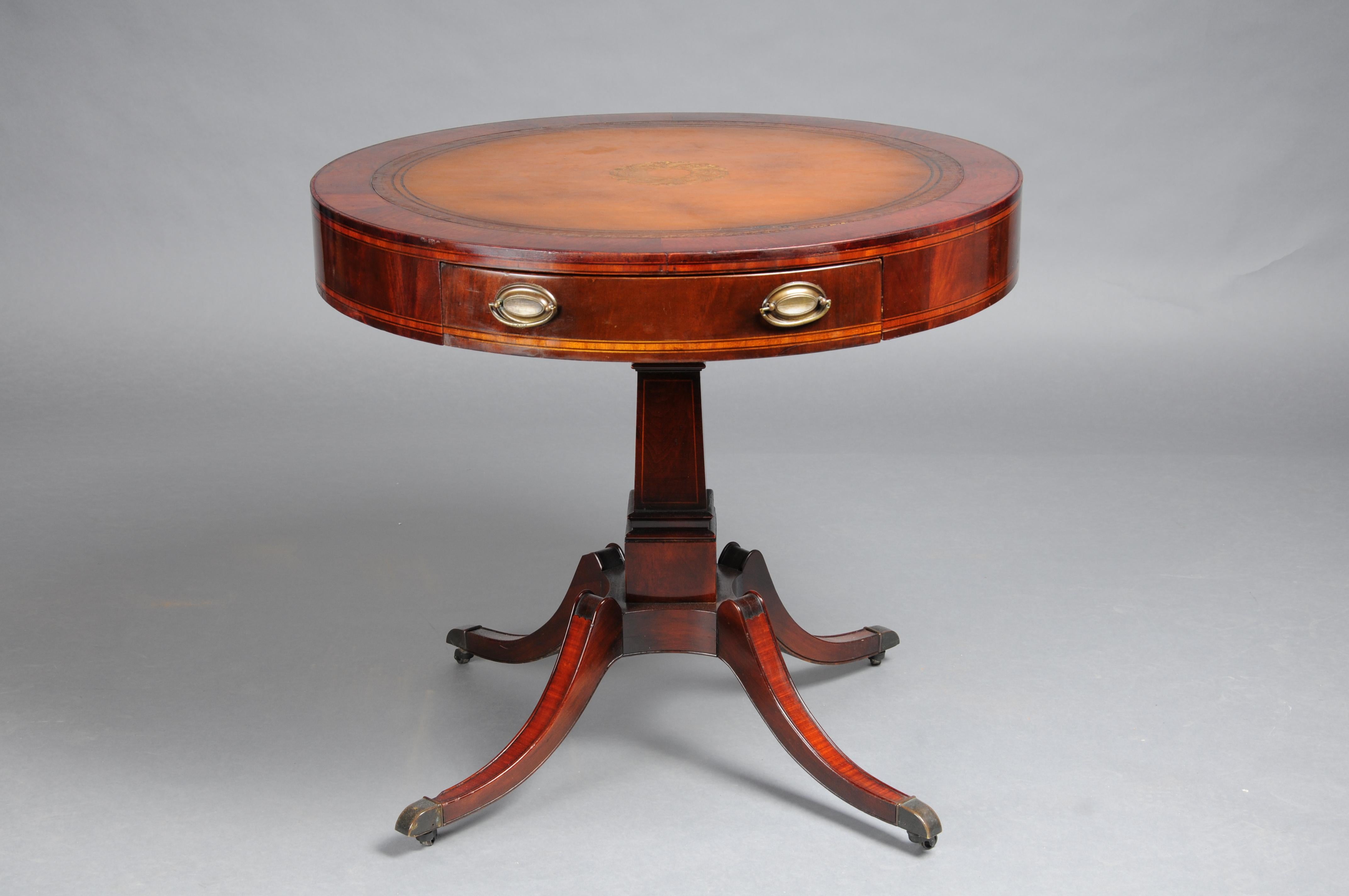 Antique classic English side table with leather top. 19th Century

Solid mahogany wood with mahogany. Round cover plate with leather plate and gold embossing. Square and profiled column shaft ending with four curved legs standing on brass roller