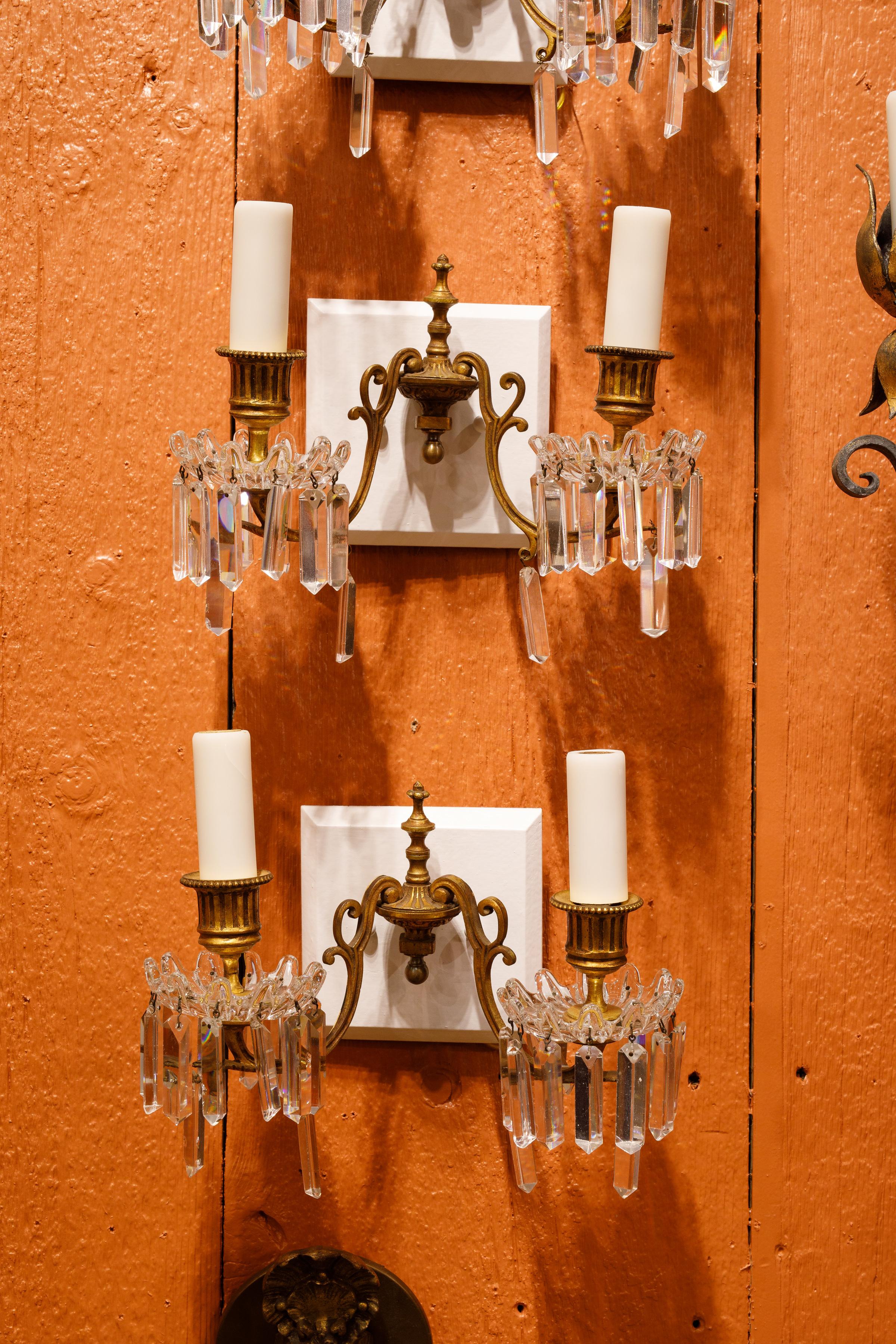 Beautifully crafted antique bronze d'ore and crystal sconces. The bronze d'ore arms are antique as are the Baccarat crystals. The antique parts have been affixed to newly carved and painted backplates that showcase their classic Louis XVI style.