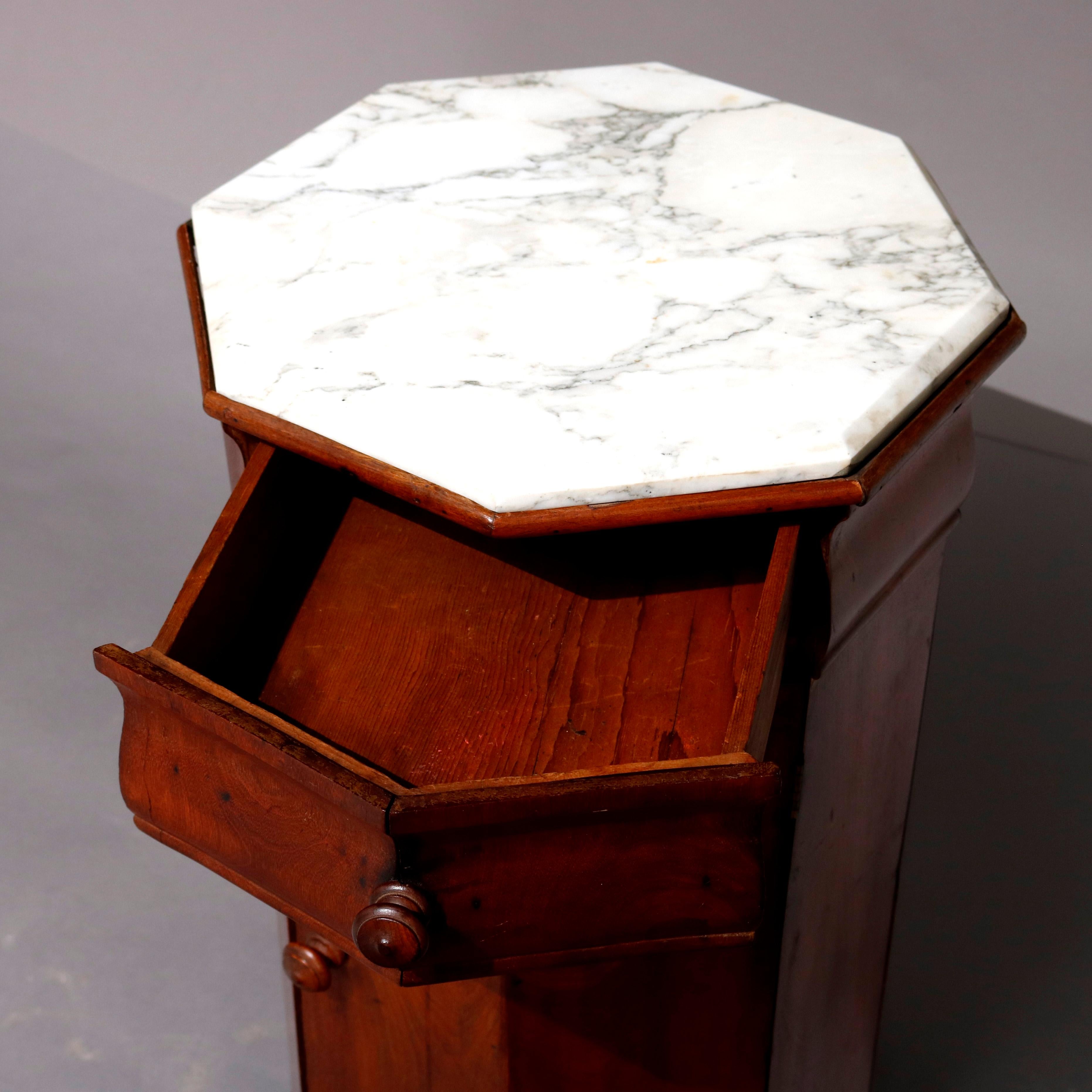 An antique classical American Empire marble-top cellarette offers flame mahogany construction in faceted octagonal form with single frieze drawer surmounting single door cabinet with shelved interior, circa 1800

Measures: 32
