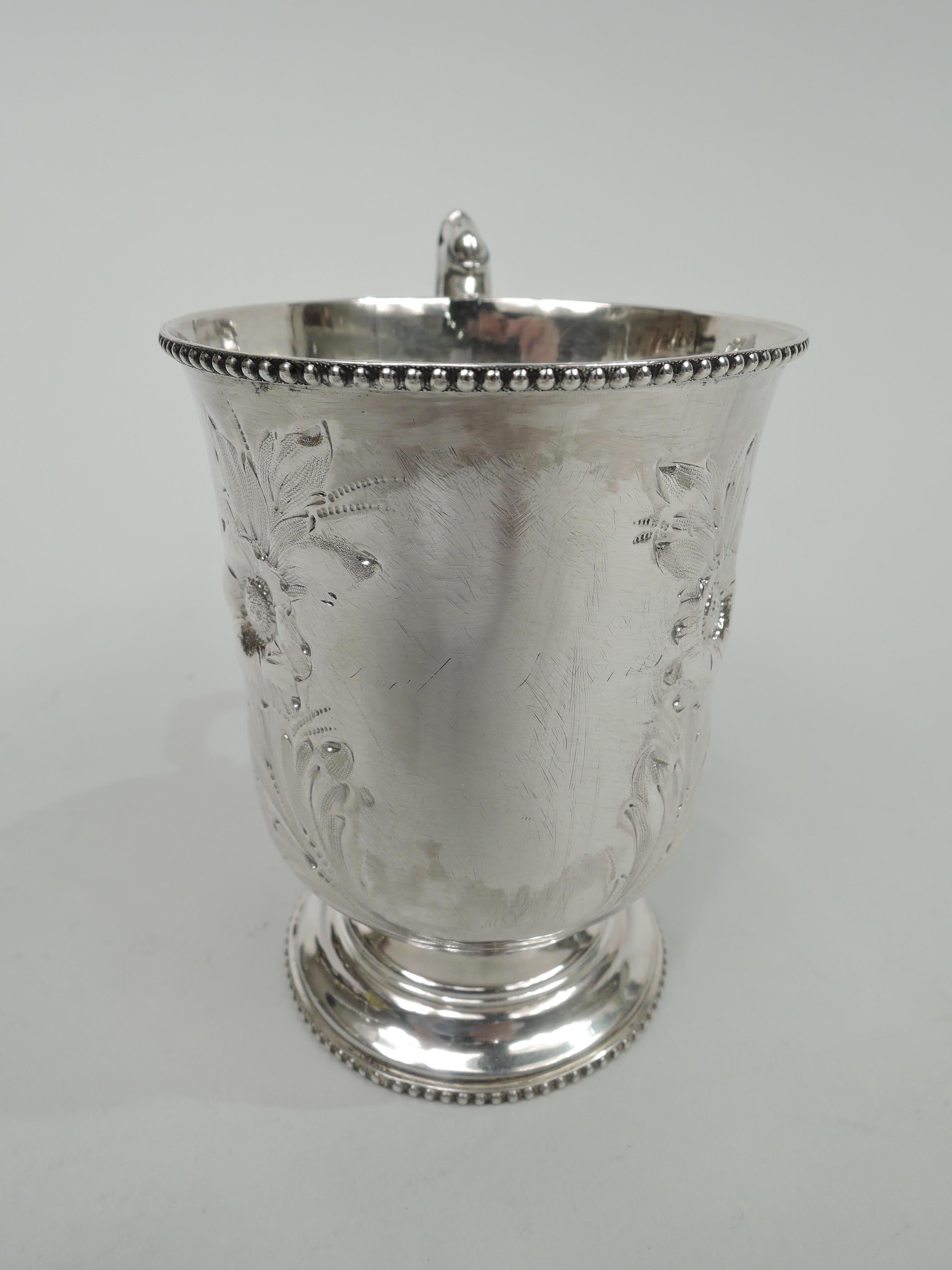Classical coin silver baby cup, circa 1850. Tapering bowl with flared rim and curved bottom. Double-scroll handle with graduated beading. Stepped foot. Chased leafing and flowering frame (vacant). Beaded rims. Unidentified marks associated with