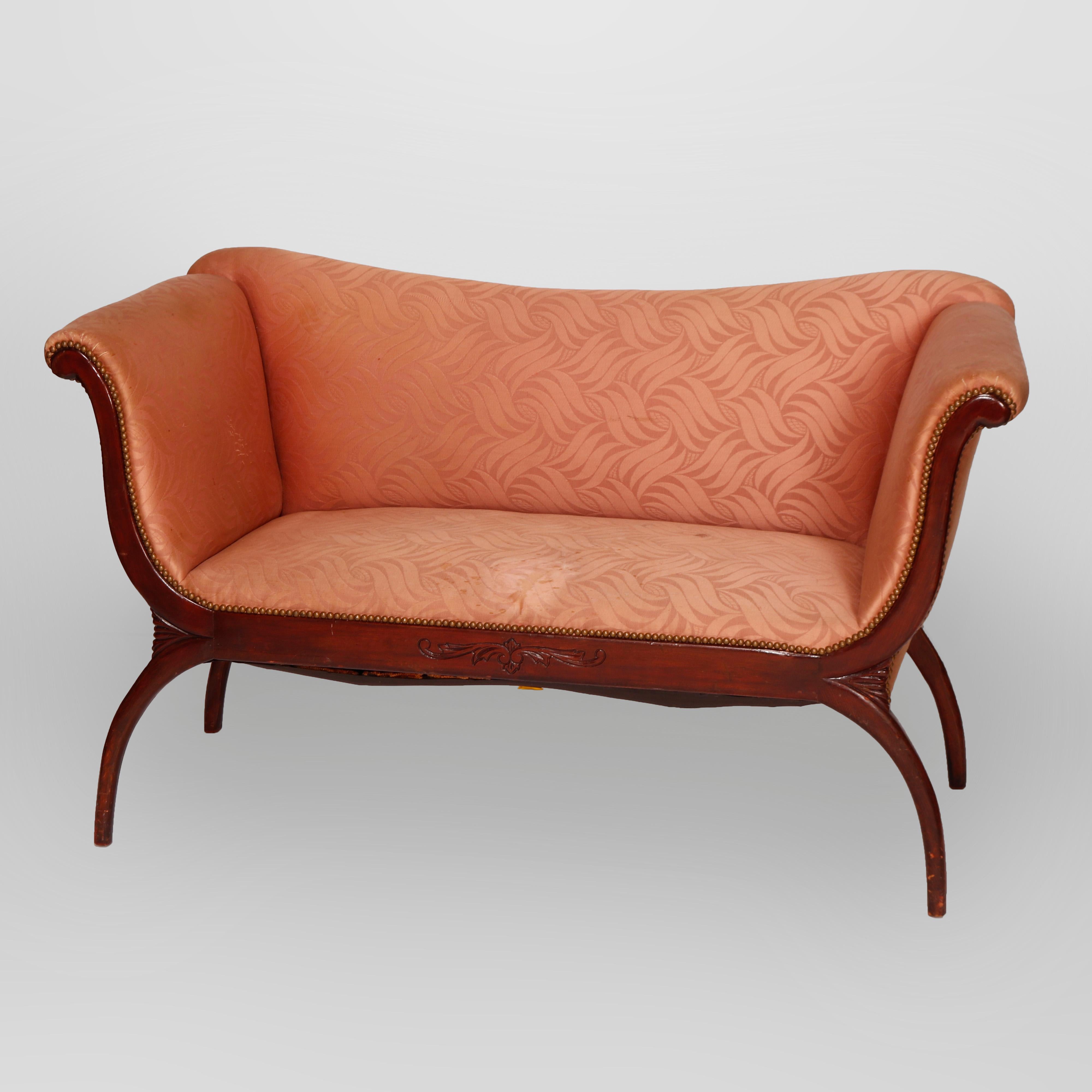 An antique classical Continental upholstered settee offers mahogany frame with scroll form arms, skirt with carved floral reserve, and raised on splayed legs, c1920

Measures- 35.5'' H x 60'' W x 26'' D; SH: 19.5''

Catalogue Note: Ask about