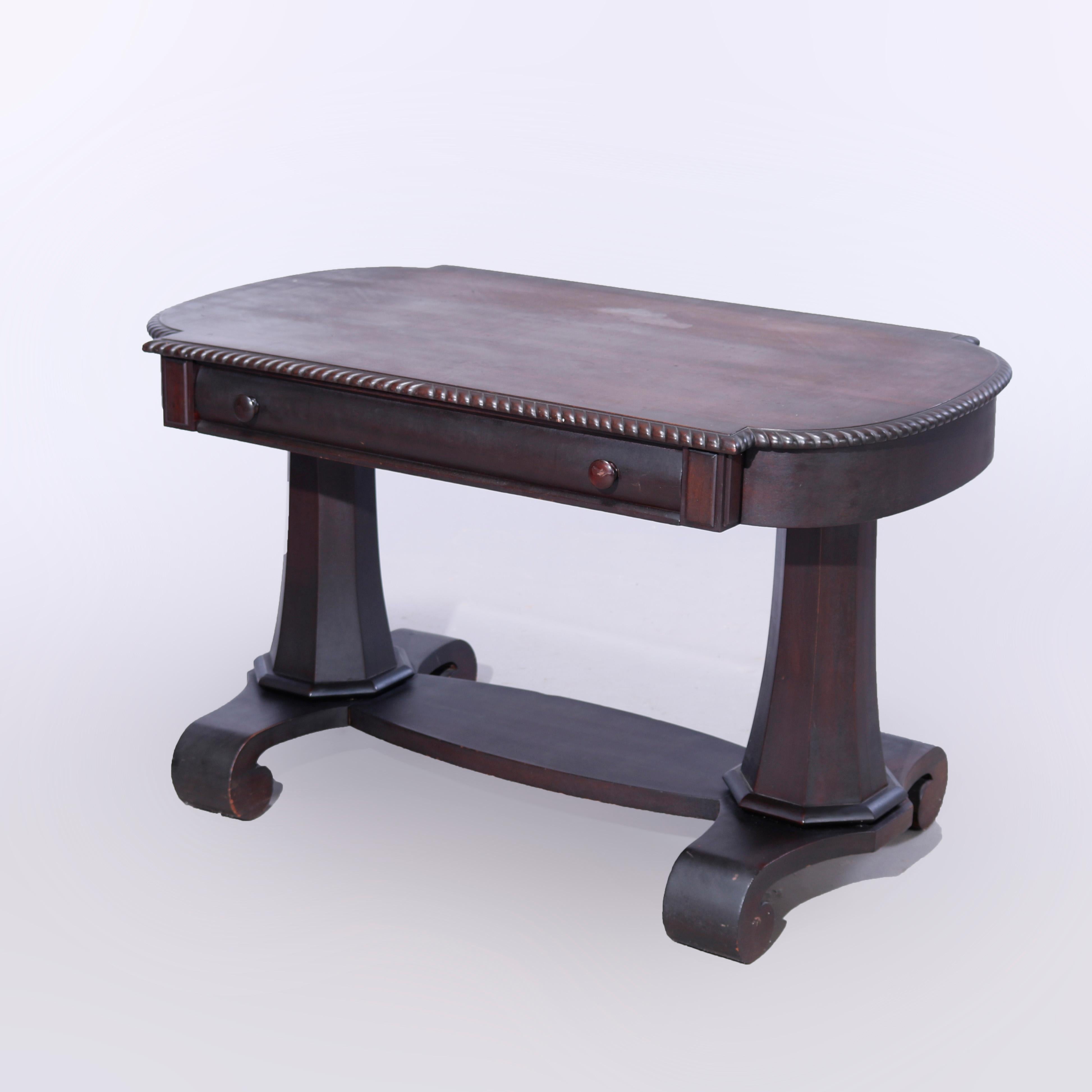 An antique Classical Greco library table offers mahogany construction in shaped oval form with top having gadroon bordering over single drawer, raised on double faceted and flared pedestals with base having scroll form feet, c1920

Measures - 28.5''