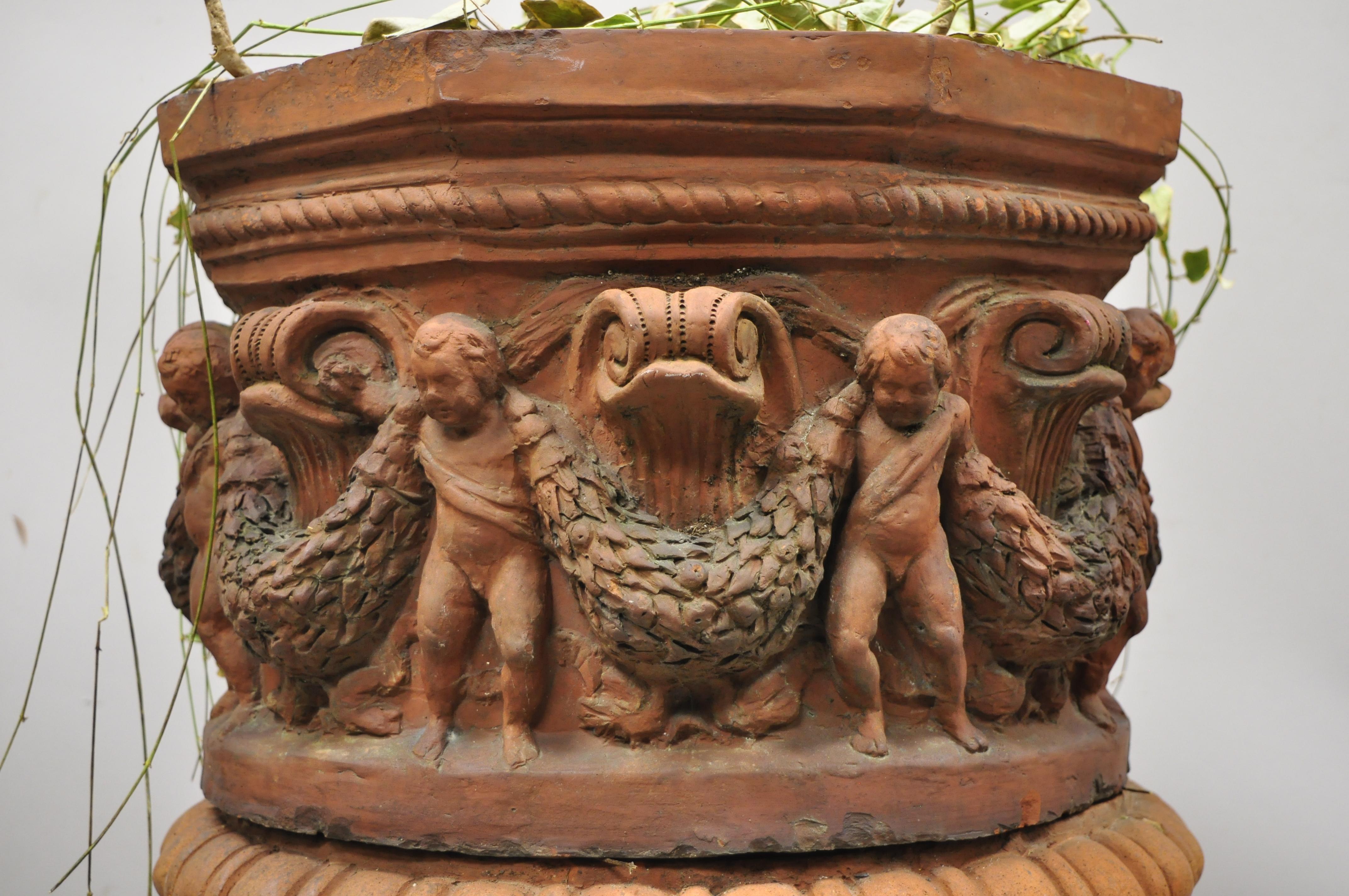 Antique classical terracotta garden pedestal planter pot with cherub figures. Item features pedestal base, ornate figural design with cherubs and faces, 2 part construction, great style and form, circa early to mid-1900s. Measurements: 29.5