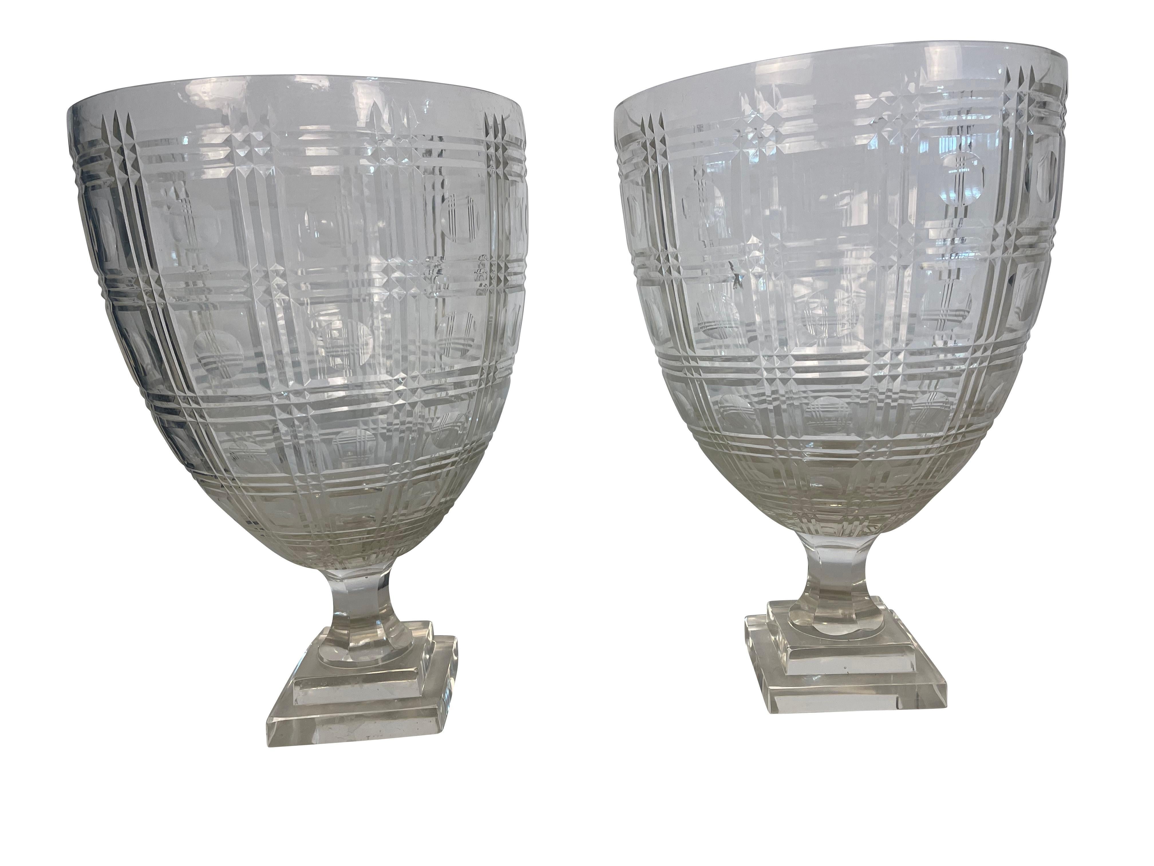 Striking pair of antique glass hurricane shades with Classic form featuring cross-hatched pattern with a dimple thumbprint design within. Lovely antique clear glass hurricanes seated on a raised pedestal with a square base.