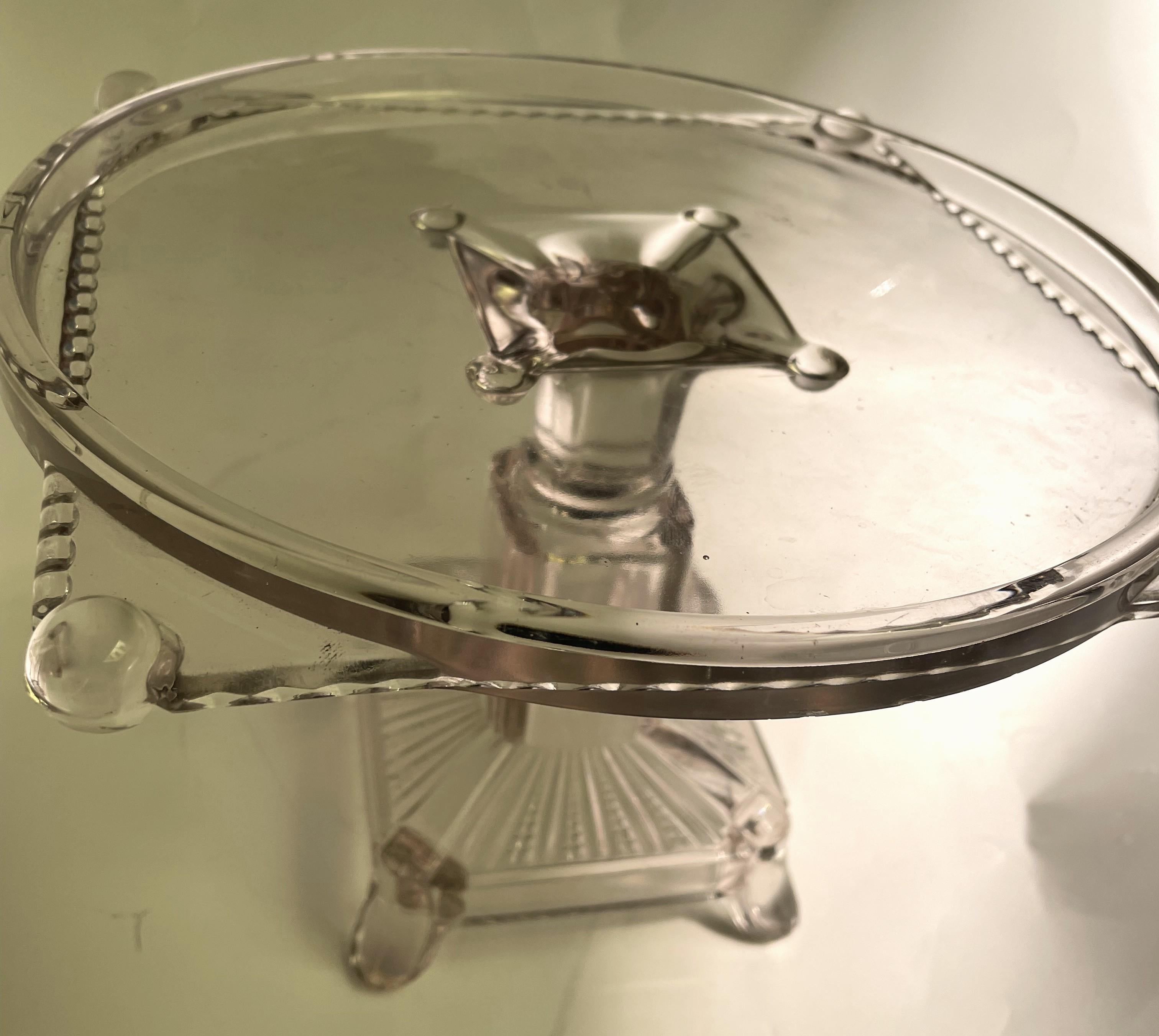 This is a fabulous antique clear glass cake stand with a wonderful pattern glass square base. The top has a round rim with four corners of a square poking out from below the rim. There is a nice design along the edge of the square a fun balls at the
