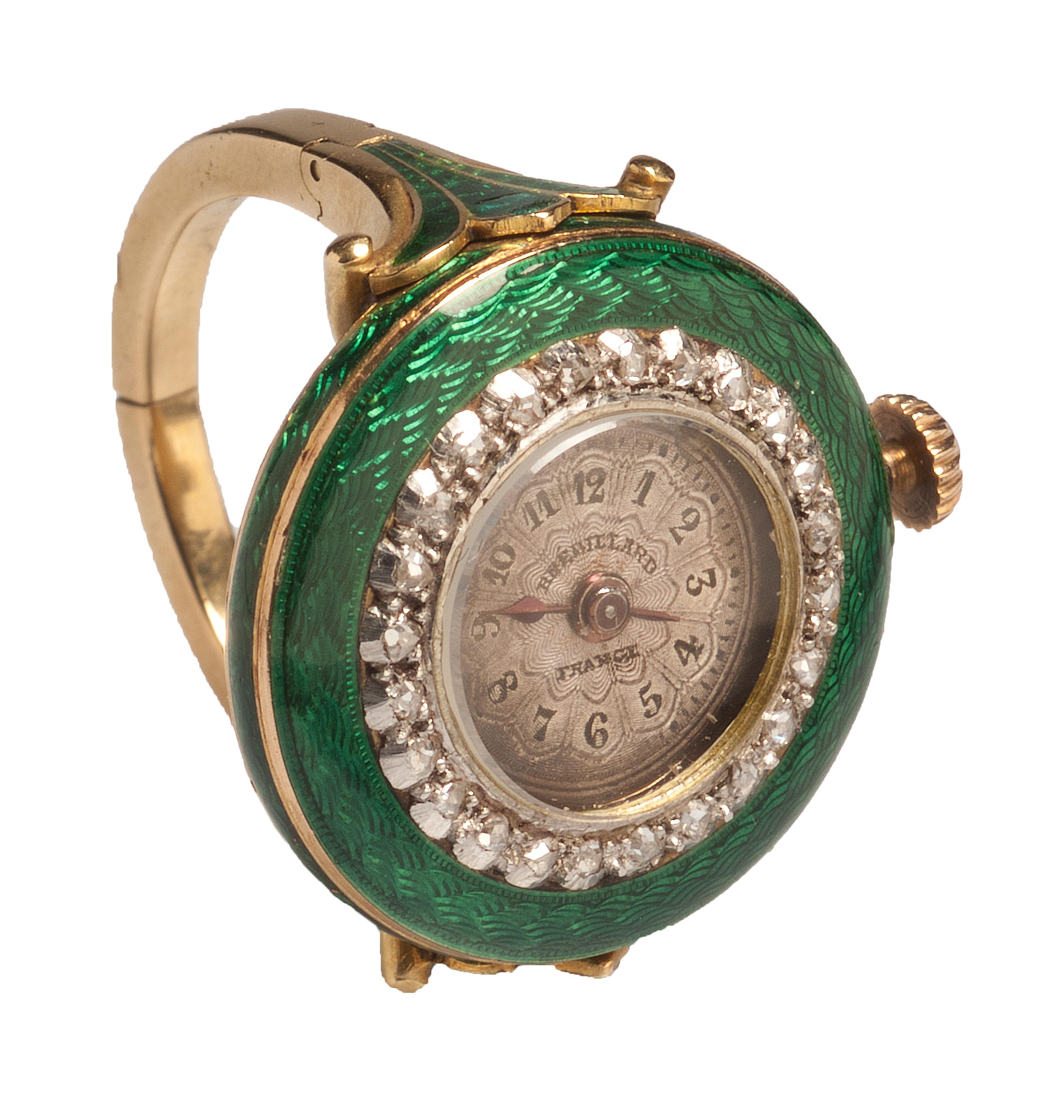 WATCH RING BY BRÉDILLARD
France, Paris, c. 1900-1910
Gold, diamonds and green enamel
Weight 11.6 gr., US size 6.5, UK size N

This gold ring is composed of a hoop with square section and hinged shoulders shaped like stylized palmettes with