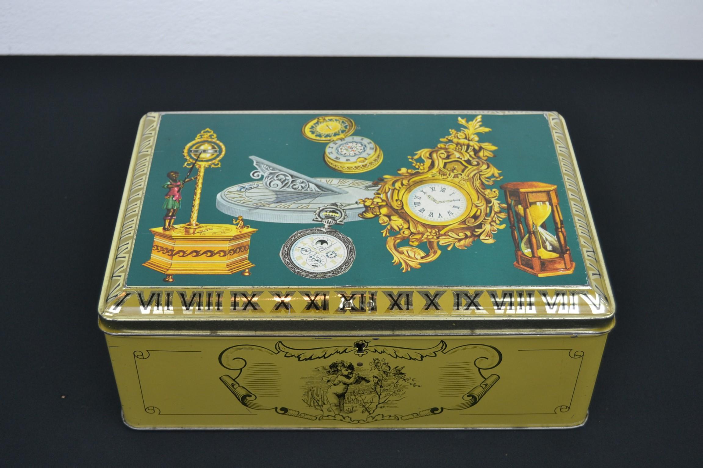 Vintage confectionary tin with theme: Antique clocks and watches, antique timepieces
This 1950s tin box is a great decorative box or storage box with beautiful design on the lid of antique timepieces like pendulum clock, antique pocket watch,