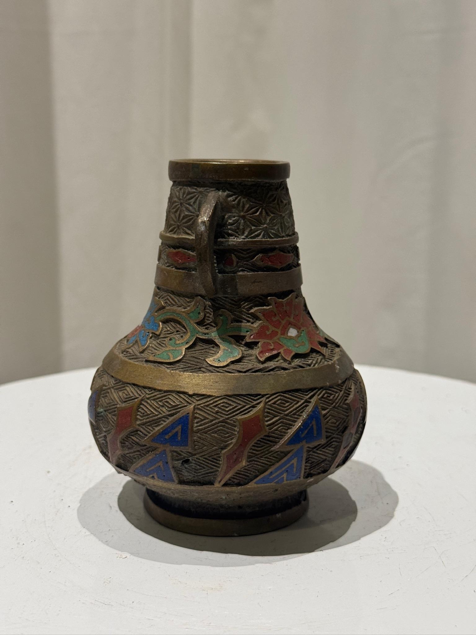 Questo squisito vaso a bocciolo in ottone antico è una rappresentazione magistrale dell'artigianato tradizionale cinese cloisonné, con intricati lavori di intarsio, delicate incisioni e un'estetica senza tempo. Il pezzo è elegantemente ornato da