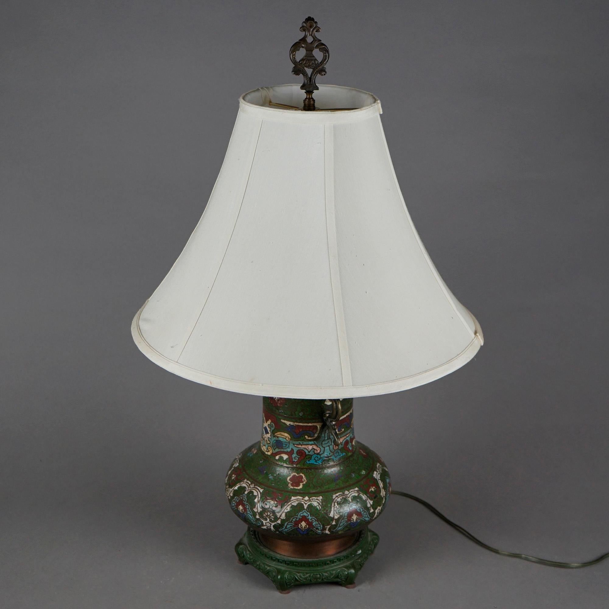 An antique double socket table lamp offers Chinese vase with Cloissone enameled allover garden design having flowers and cast figural dragon double handles, seated on carved hardwood base, wired for US electricity, c1920
 design

Measures- 27.5''H x