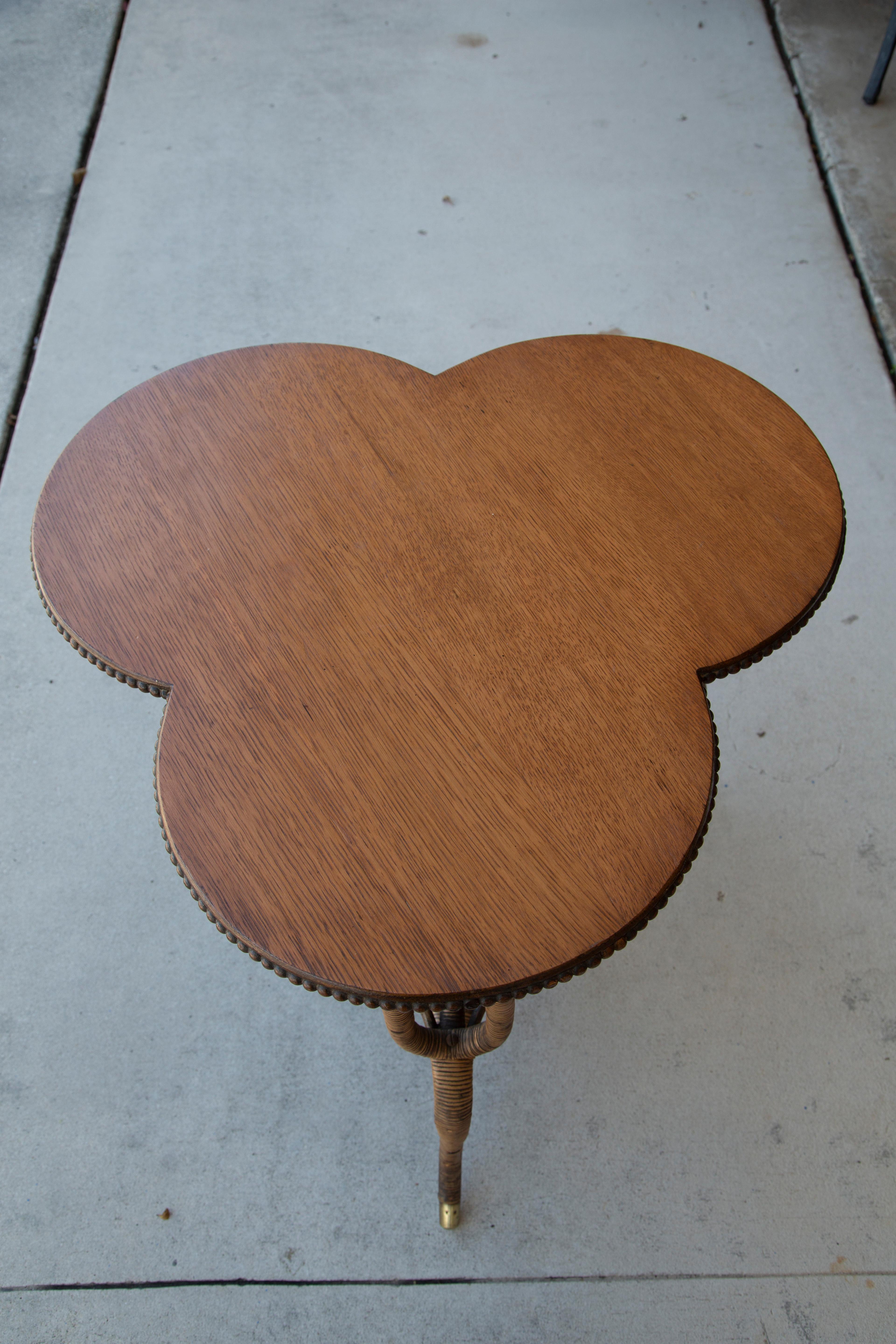 Antique oak clover leaf shaped table with wood beading surrounding the edges. Curved legs with brass trimmed ends.