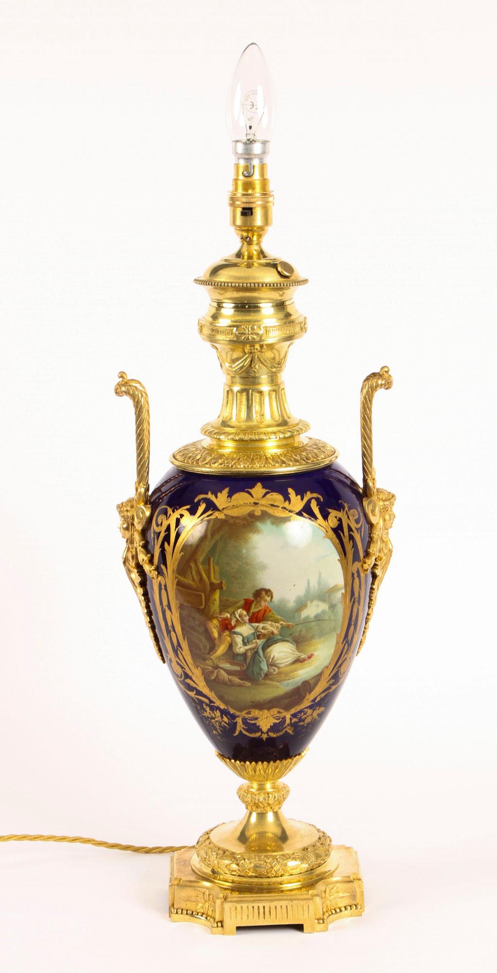 This is a stunning large antique French Sevres cobalt blue hand painted porcelain and ormolu-mounted vase circa 1880 in date, later converted into a lamp.

The vase shaped porcelain body is painted with gilt-framed panels depicting a classical