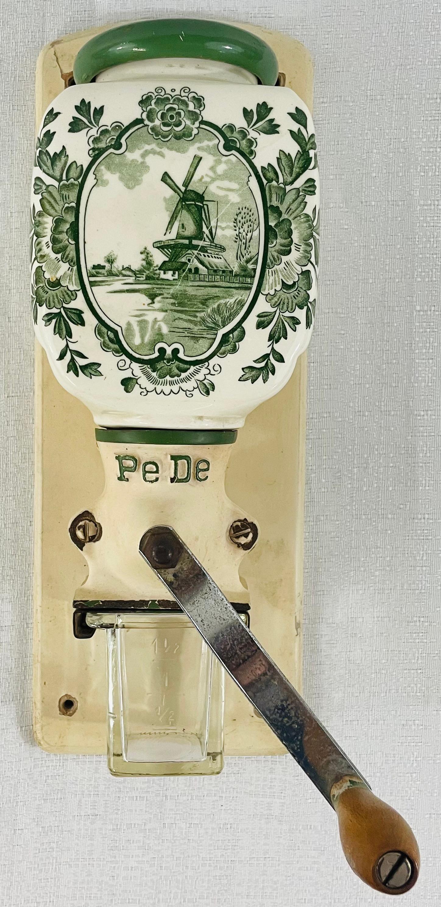 A 1930's antique Coffee Grinder Delft Dutch Green Wall Mill PeDe Kitchen from the Zassenhaus era and made in Holland Netherlands. The Coffee grinder features a porcelain jar with a Delft scene on the porcelain hopper hand painted in green. The