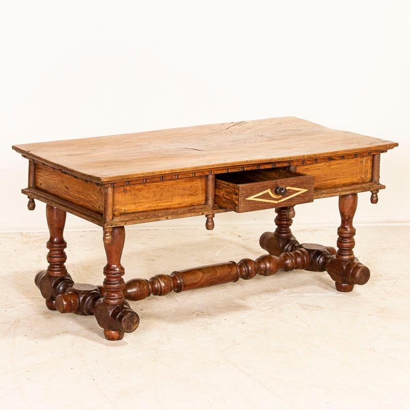 This highly unusual coffee table is a special find. The heavily turned trestle base, wood pegs (vs nails), simple inlay in the single drawer and even the wood inlay repairs seen in the top all add to the unique appeal of this one of a kind table.