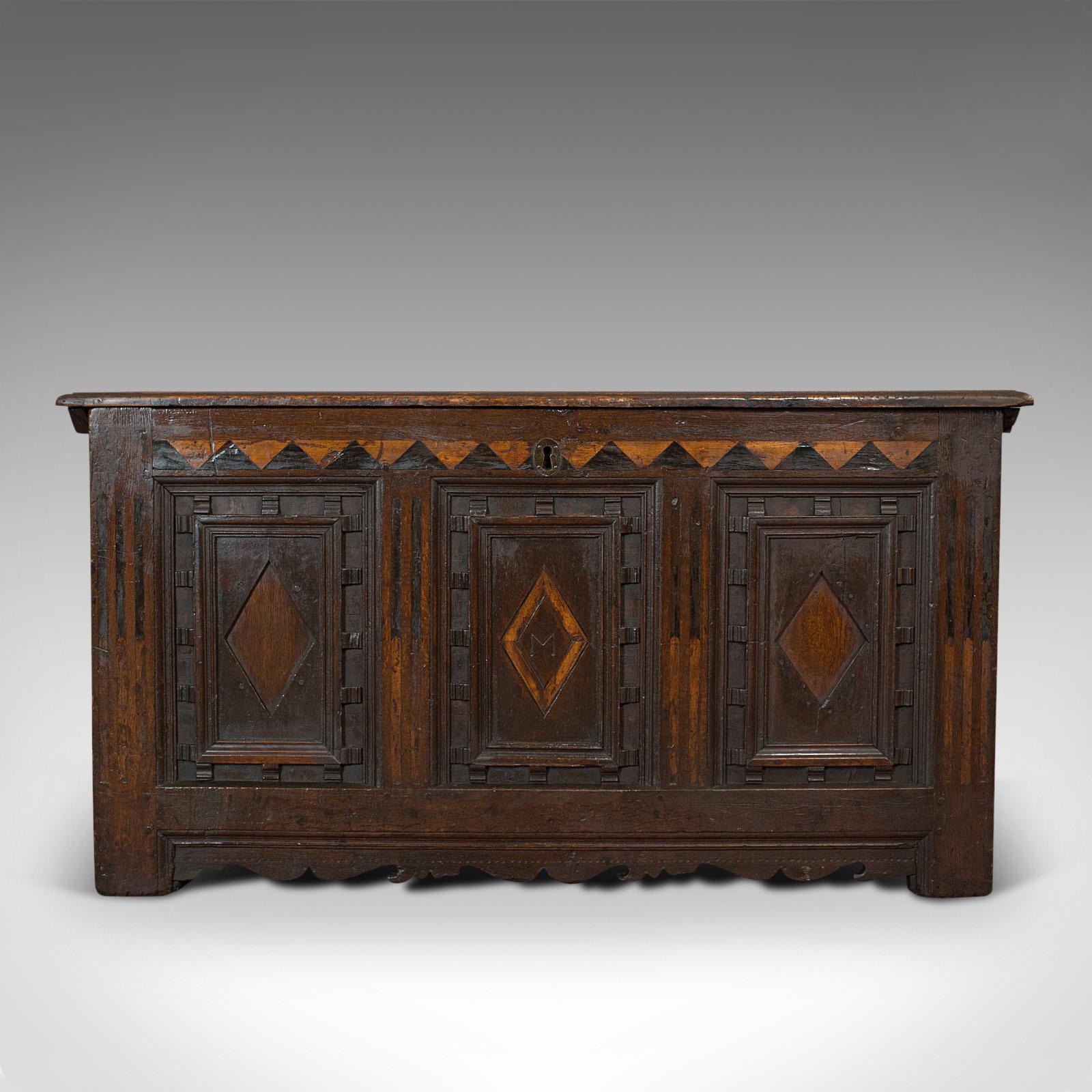 This is an antique coffer. An English, oak three-panel linen chest or trunk, dating to the William III period, circa 1700.

High quality and ornate antique coffer
Displays a desirable aged patina
Dark English oak shows fine grain interest and