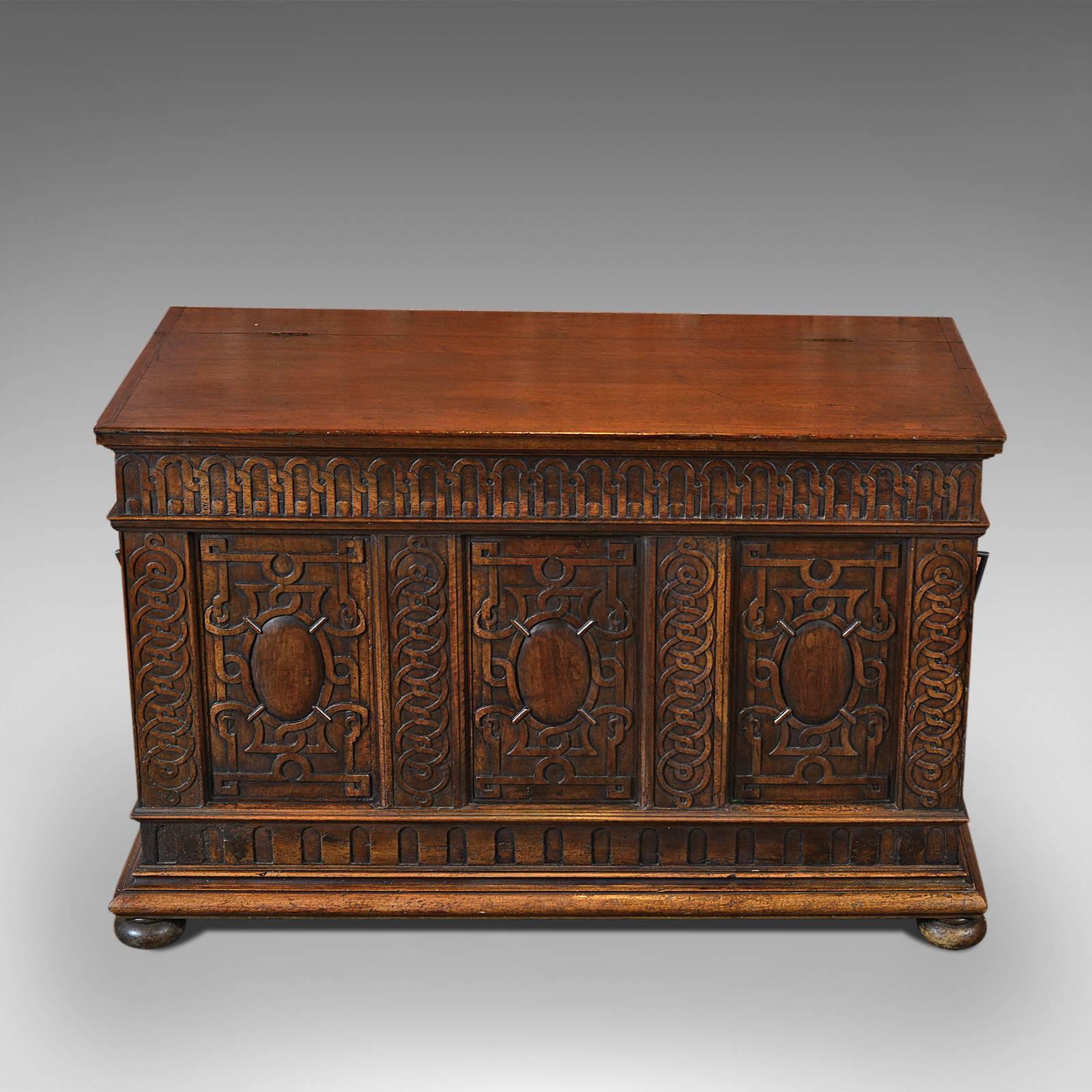 This is an antique coffer, French, walnut, dating to circa 1800.

Substantial and imposing, this coffer is vigorously carved on three sides beneath a hinged plank lid displaying wonderful color and patina.

Four flat bun feet raise the large