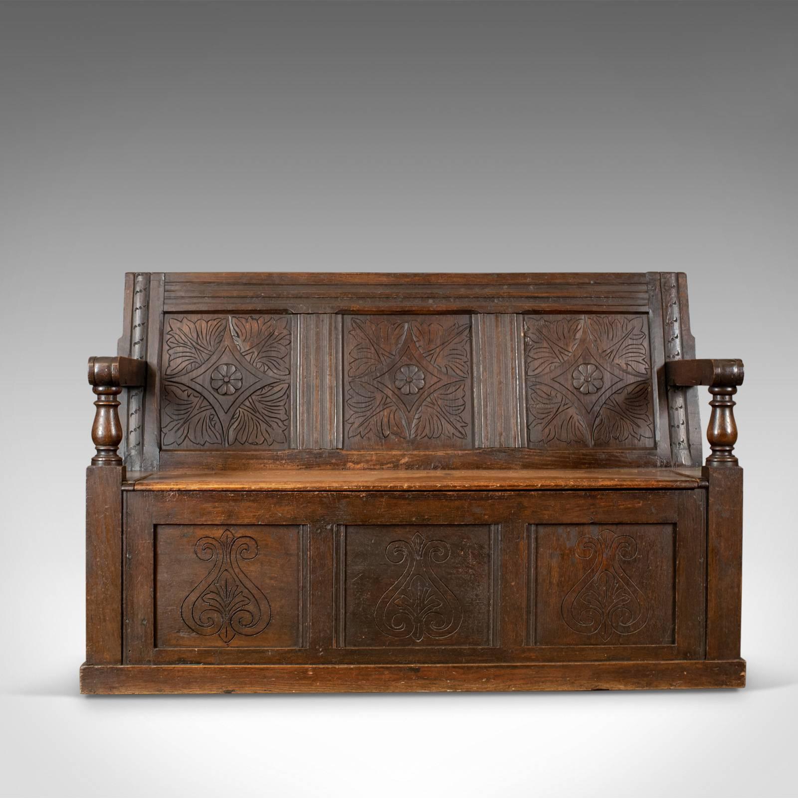 This is an antique coffer settle, an English oak bench chest seat dating to the early 18th century circa 1700 and later.

Good color in the lustrous wax polished finish
Carved interest with a desirable aged patina
Pegged and panelled