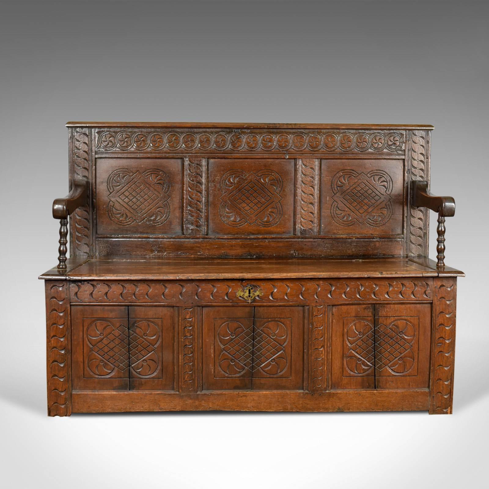 This is an antique coffer settle, an English oak hall bench seat dating to the early 18th century circa 1700 and later.

Good color in the lustrous wax polished finish
Carved interest with a desirable aged patina
Of quality pegged and panelled