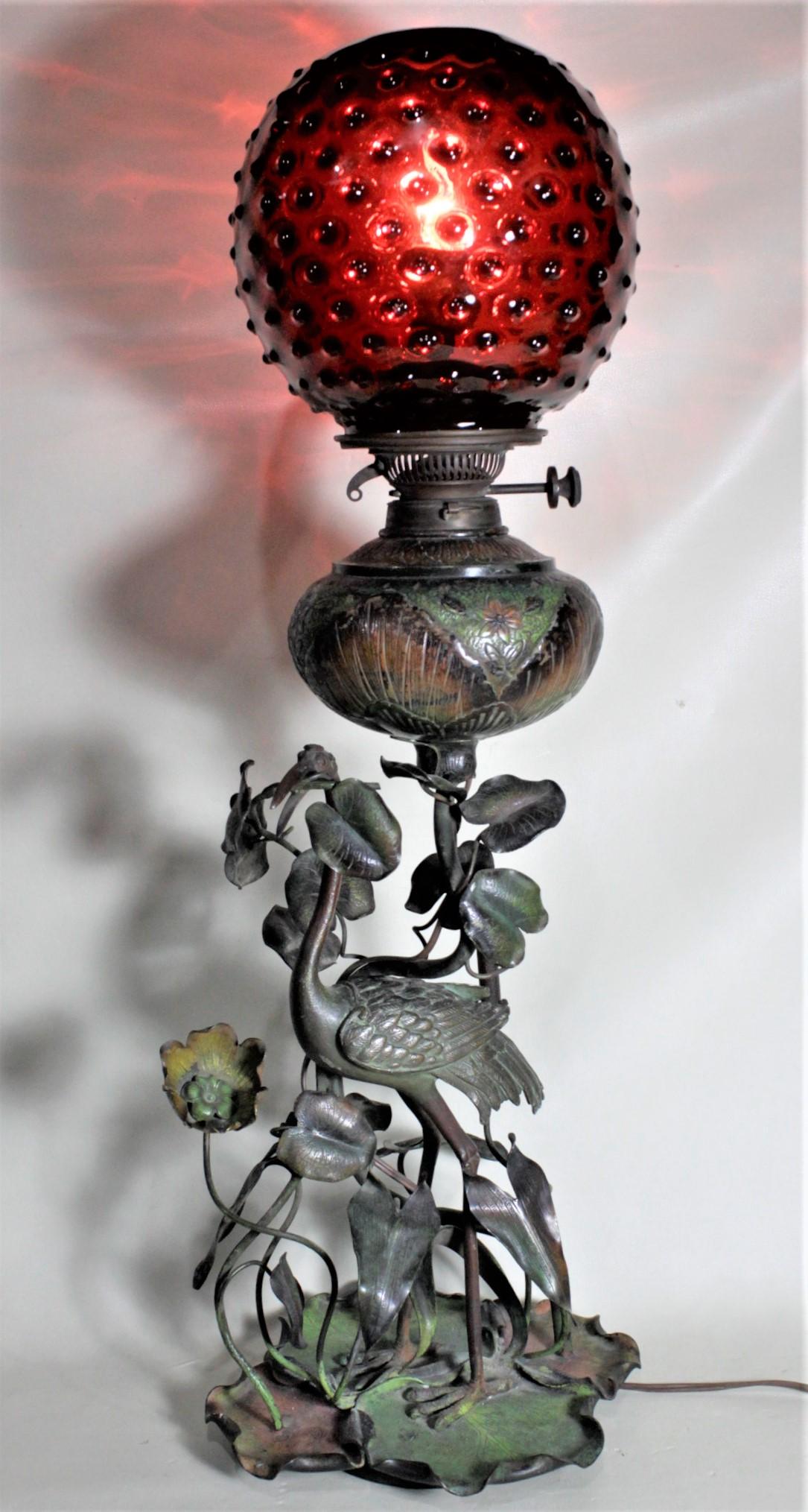 This cast bronze and cold-painted converted oil lamp is unsigned, but presumed to have been made most likely in Austria in circa 1890 in the period Victorian style. This electrified former banquet oil lamp consists of a large cast Heron or shore