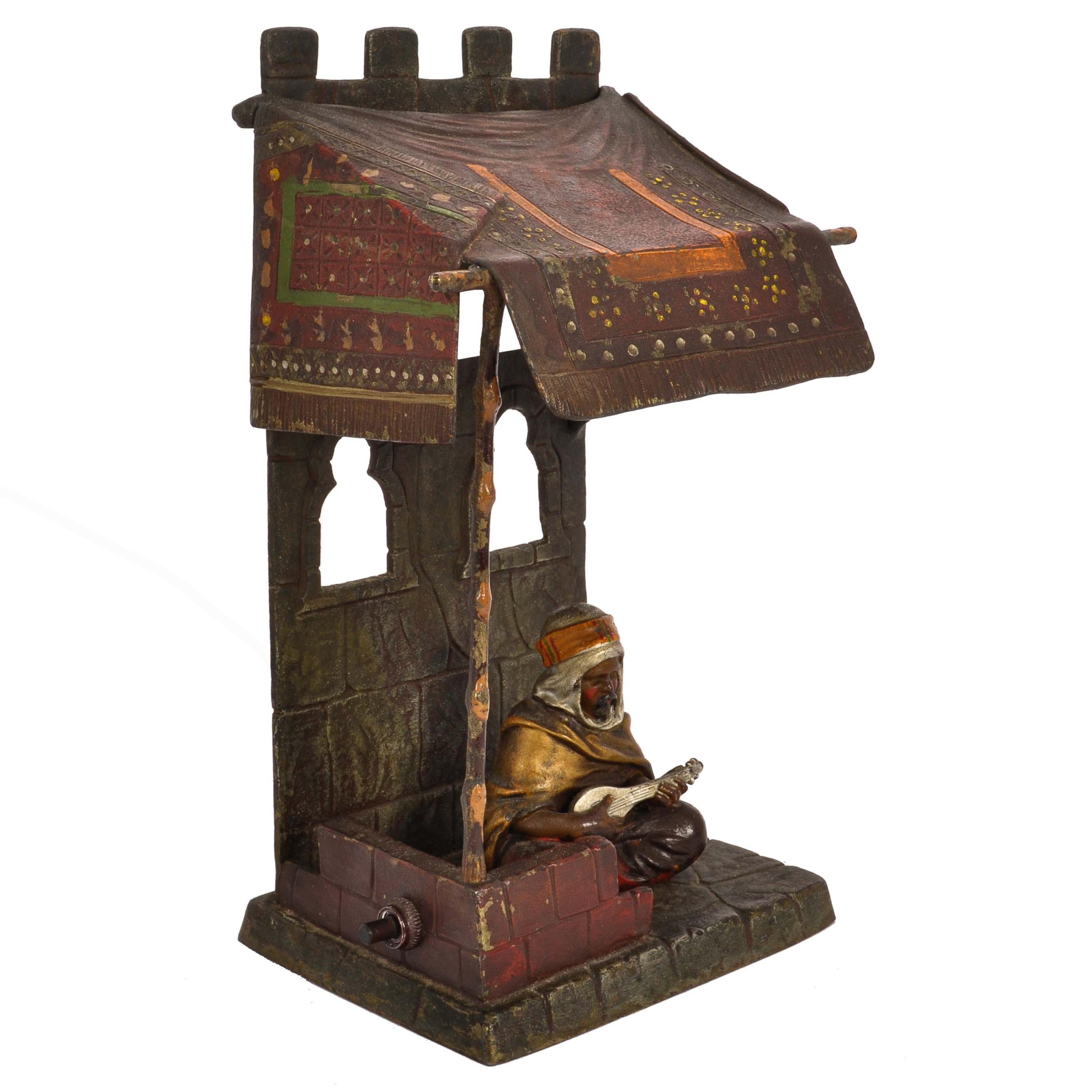 A good antique cold painted bronze Orientalist/Arab Franz Bergman style lamp, circa 1920.
The lamp depicts an Arab musician seated in front of a fort playing an Oud (Arabic lute) he is sheltered from the sun under an oriental rug as a canopy. The