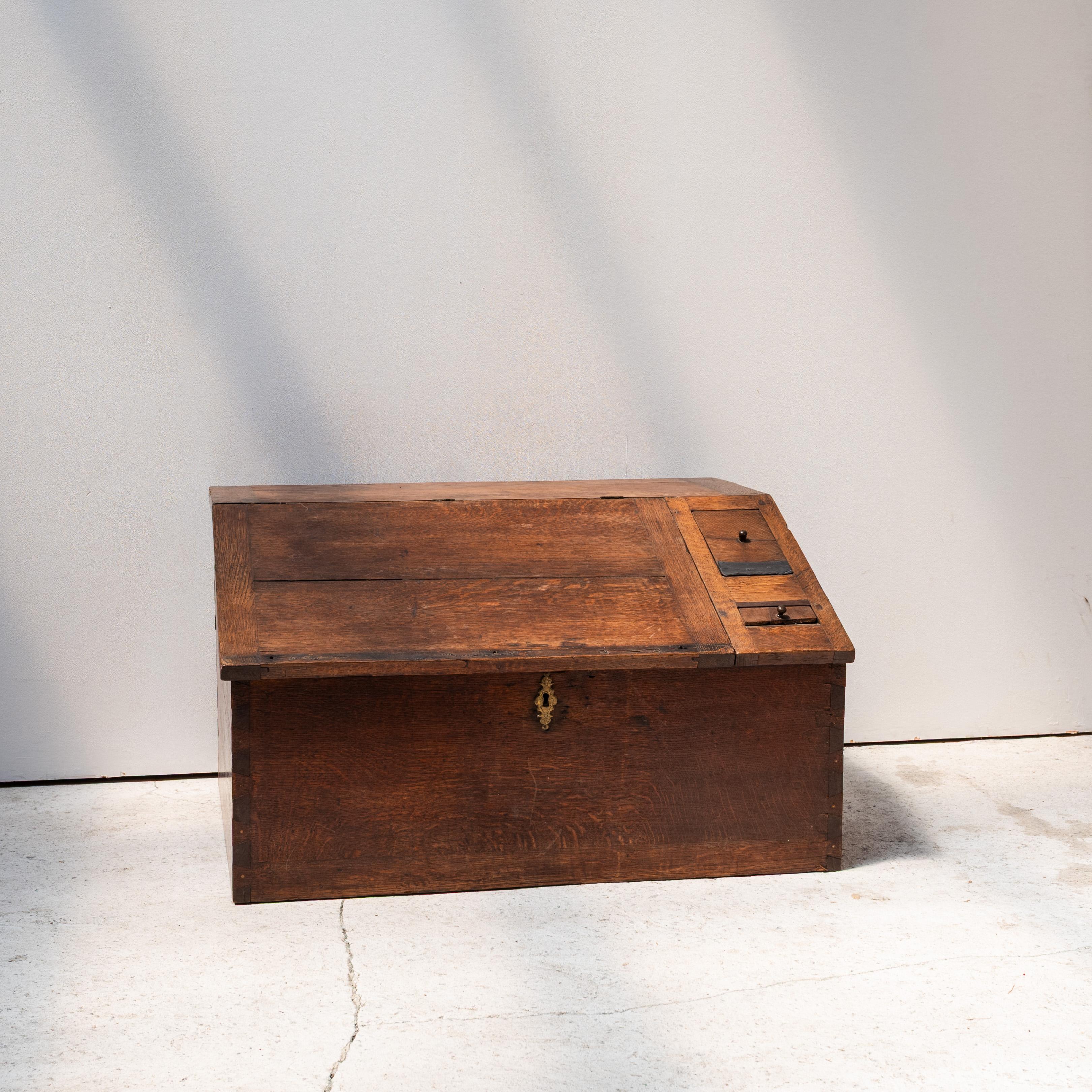 A rare  storage chest with a beautifully sectioned interior, likely used as a writing slope or merchant’s chest. The exterior presents a restrained, architectural simplicity with clean planes of solid wood and a subtle brass escutcheon. Once opened,