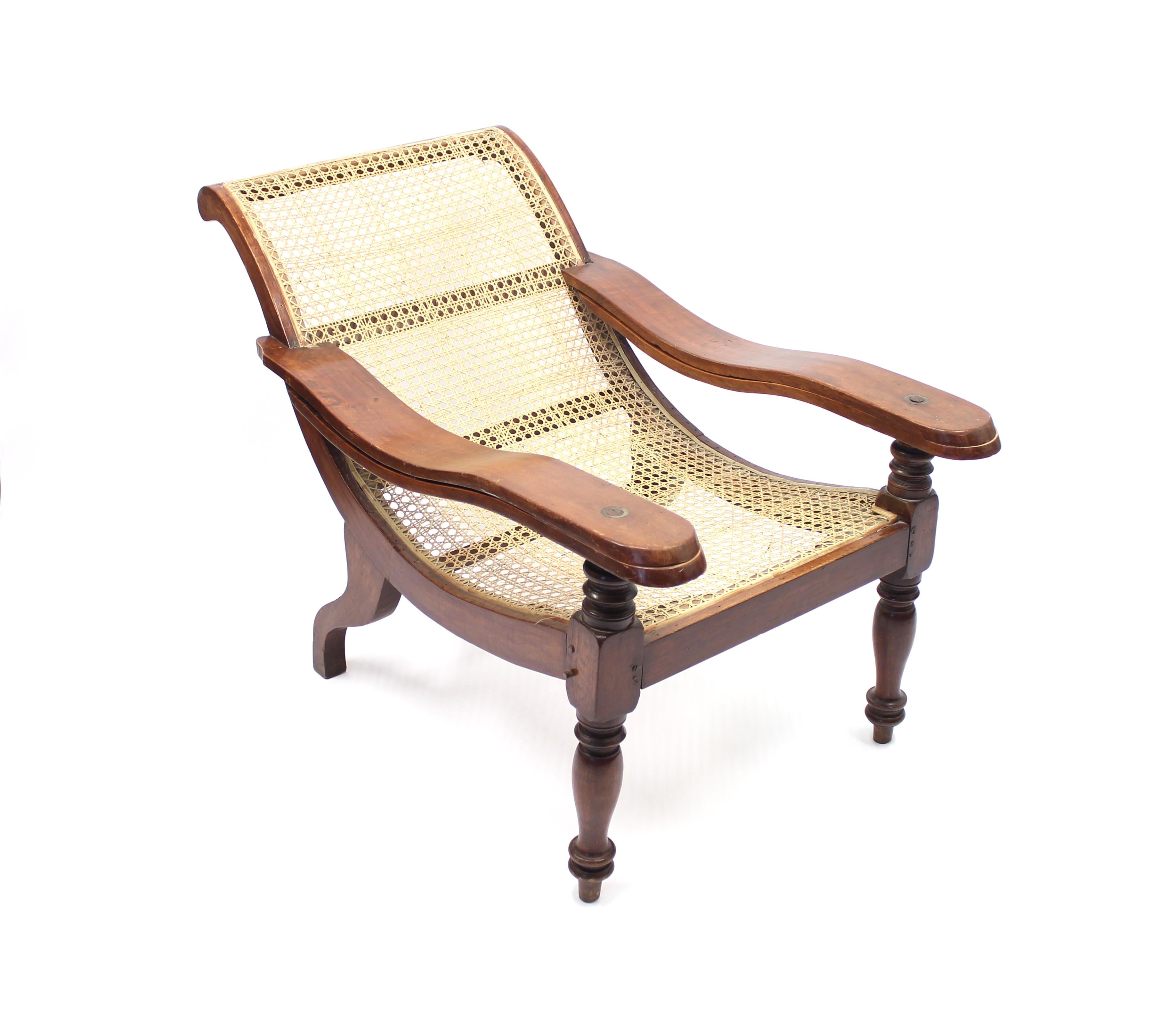 Antique late 19th century colonial plantation chair with foldable leg rests, rattan seat of later date. Frame of exotic wood with lathed front legs.