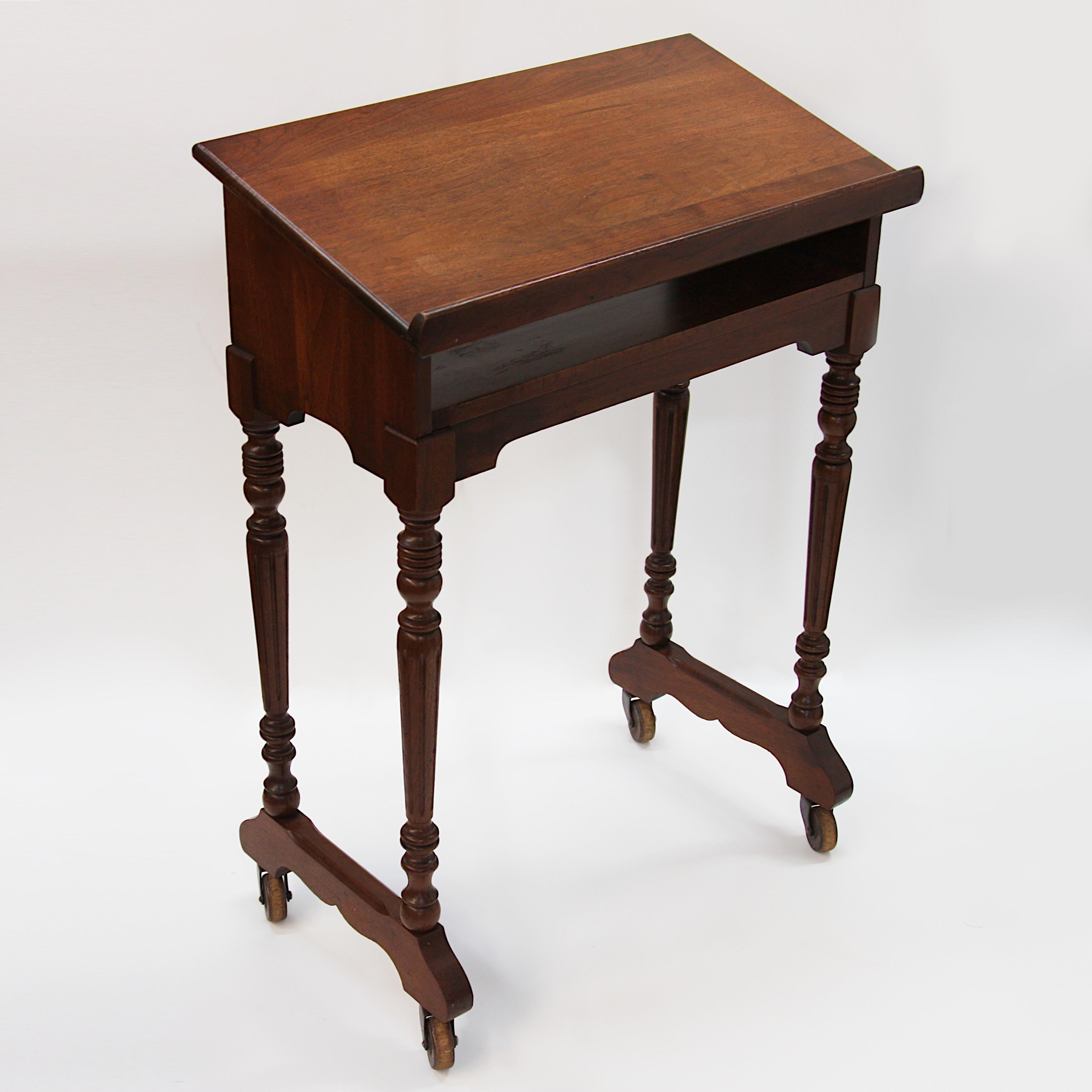 Wonderful Colonial Revival Bible/book stand. Stand features solid walnut construction, turned legs, and wooden wheel casters. An excellent original example and a charming size that could be used almost anywhere!