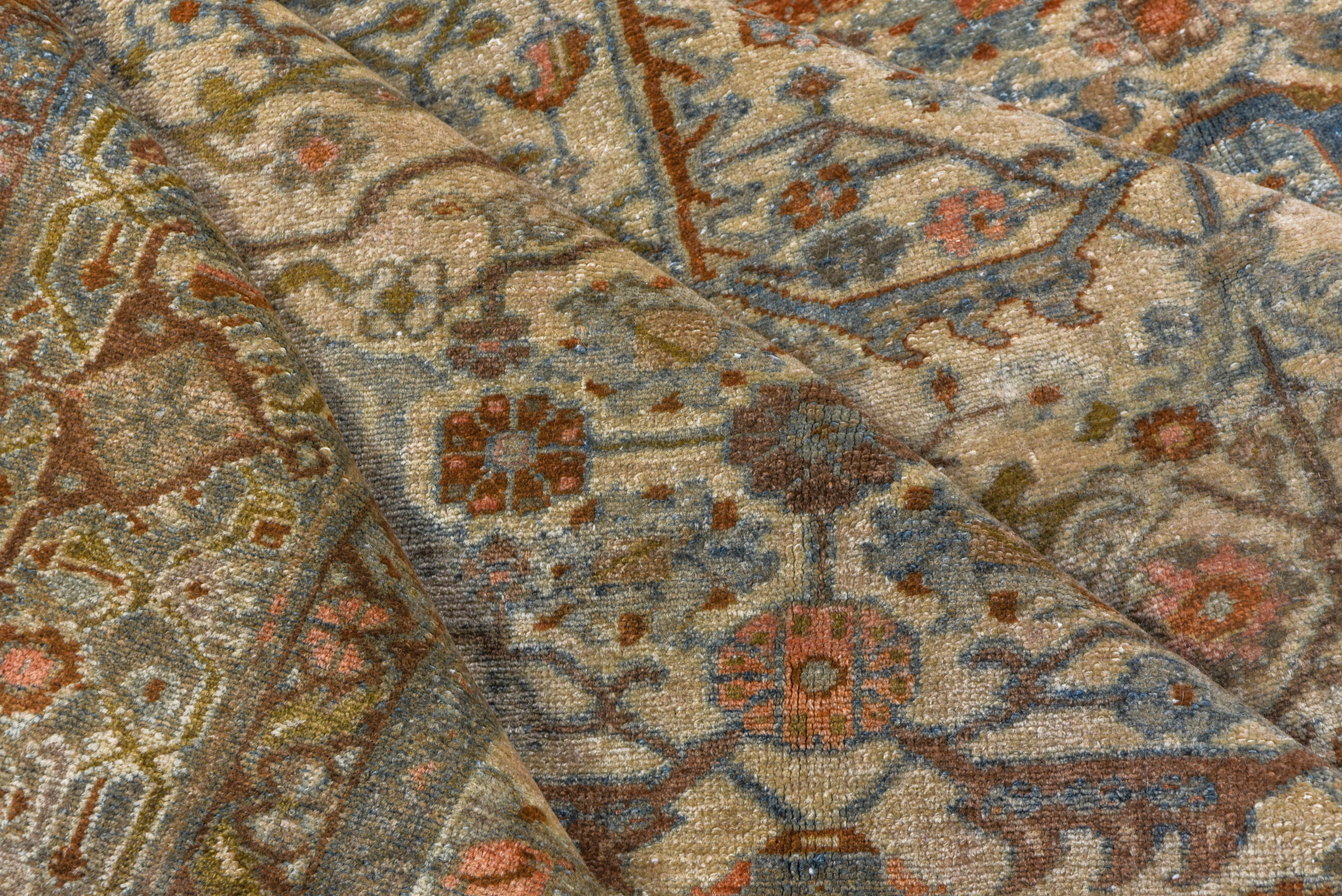 Serrated leaves, vinery lozenges and hexagons, rough small palmettes and lots of floral infill decorate the ecru field of this west Persian rustic carpet .A medium blue border shows a reversing turtle palmette design and rust accents are everywhere.