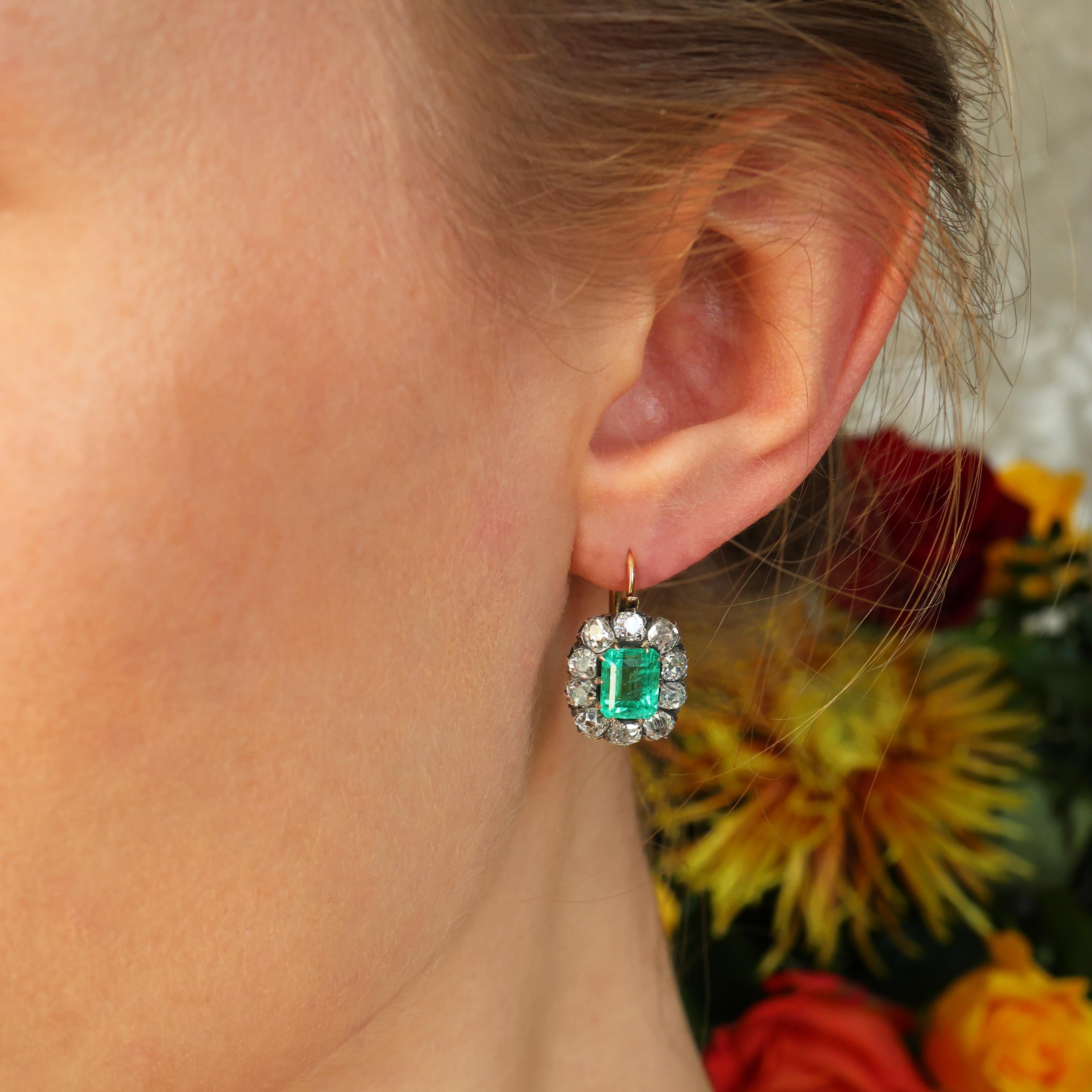 Paire de boucles d'oreilles anciennes en émeraude et diamant, avec des émeraudes de Colombie taillées en émeraude, en serti griffe, entourées de dix diamants taillés dans des mines anciennes, en serti couronne en argent, sur des montures en or 18ct,