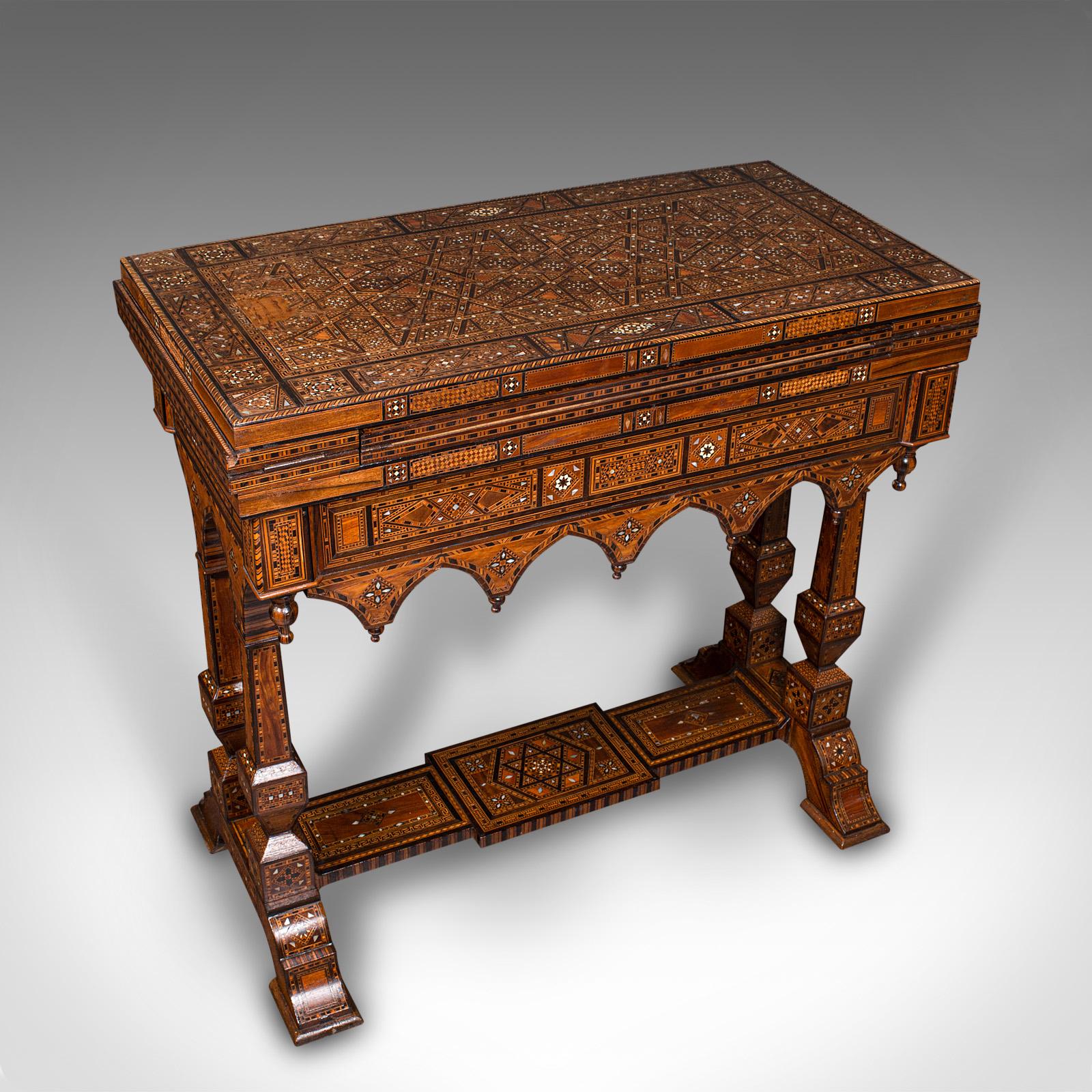 
This is an antique combination games table. A Middle Eastern, inlaid olivewood and exotic wood metamorphic chess and backgammon table, dating to the late Victorian period, circa 1900.

Strikingly ornate, with an exceptional metamorphic form to host
