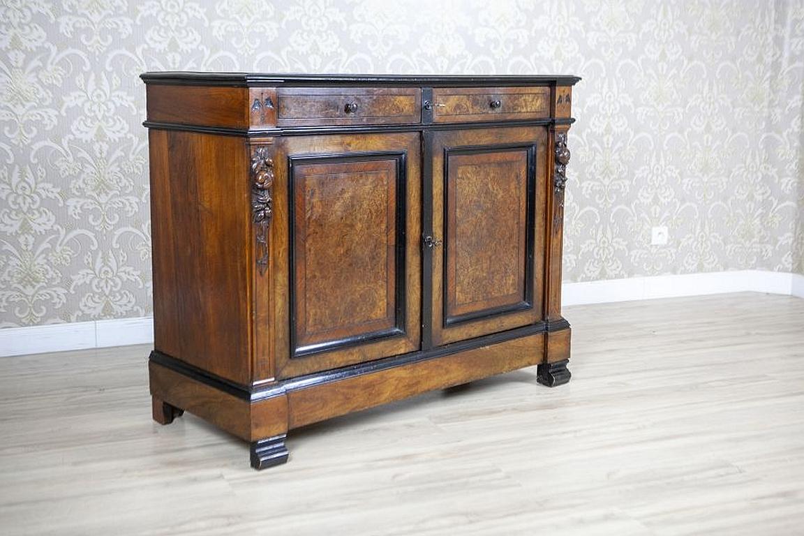 Antique Commode from the Late 19th Century Veneered with Walnut

We present you this piece of furniture composed of a corpus with two drawers under the top.
The door leaves are flanked by pilasters with elaborate floral carved patterns.
The whole