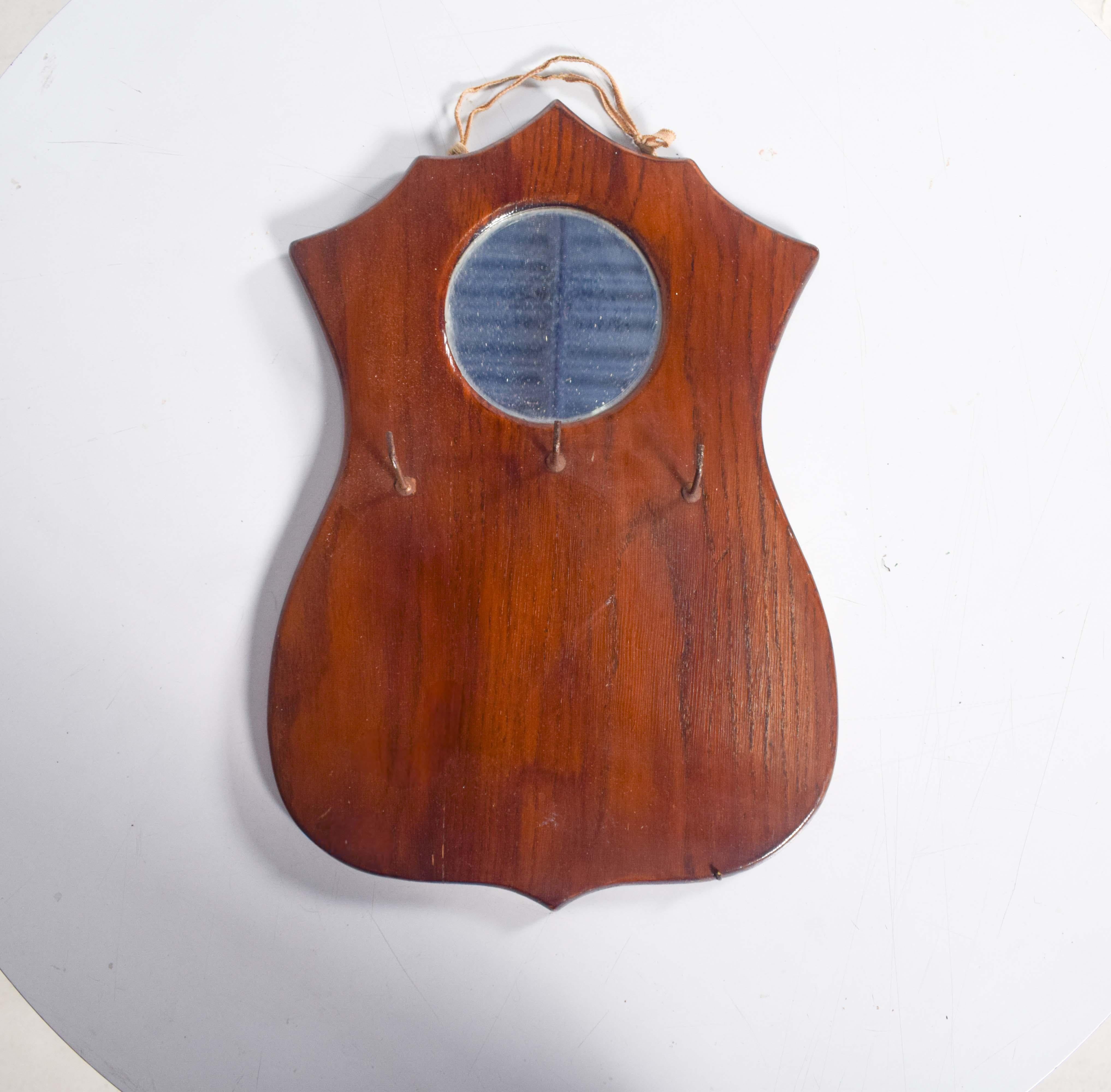 Dieser kompakte Schlüsselanhänger ist aus hochwertigem Holz geschnitzt und mit einem eleganten Wappendesign versehen. Oben ist ein runder Spiegel eingebaut, der für Funktionalität und einen Hauch von Raffinesse sorgt. Dieses Accessoire ist ideal für