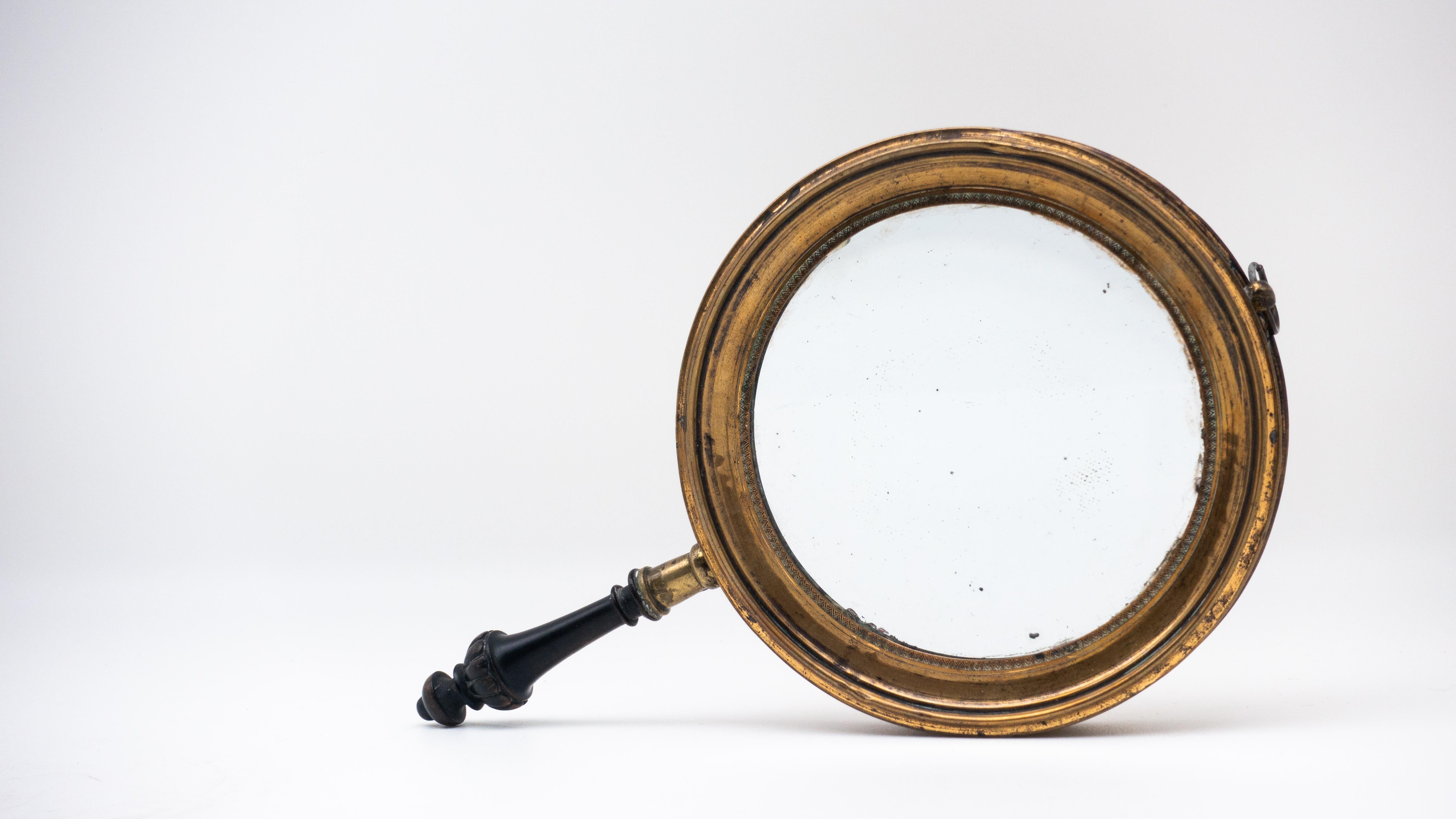 Antique concave brass and carved wood hand mirror, 19th century.