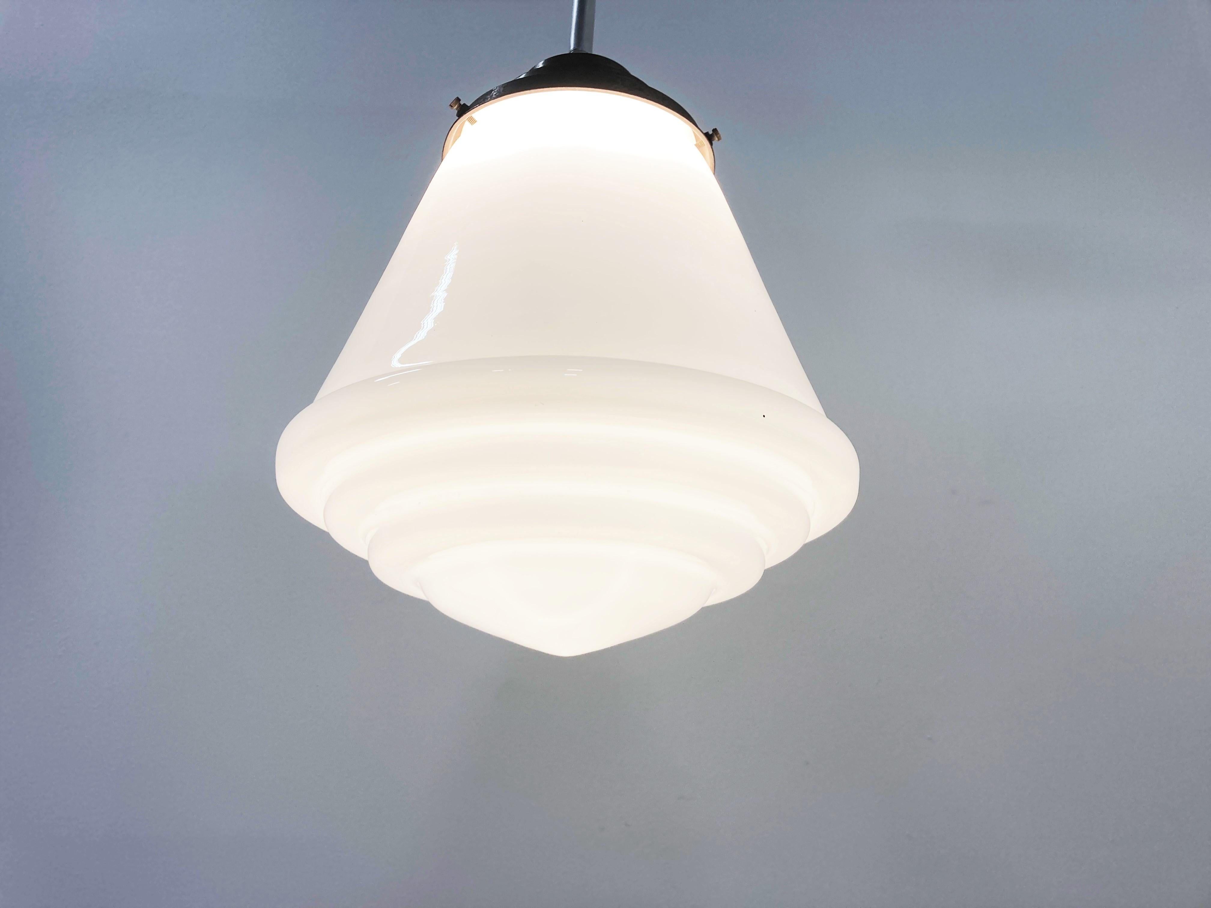 Antike konisch geformte Art-Deco-Hängeleuchte für den Flur.

Diese Lampe ist sehr typisch für die Art-Deco-Ära und wurde häufig in Fluren, Büros oder größeren öffentlichen Räumen aufgehängt.

Die Lampe hat die originale vernickelte Stange und