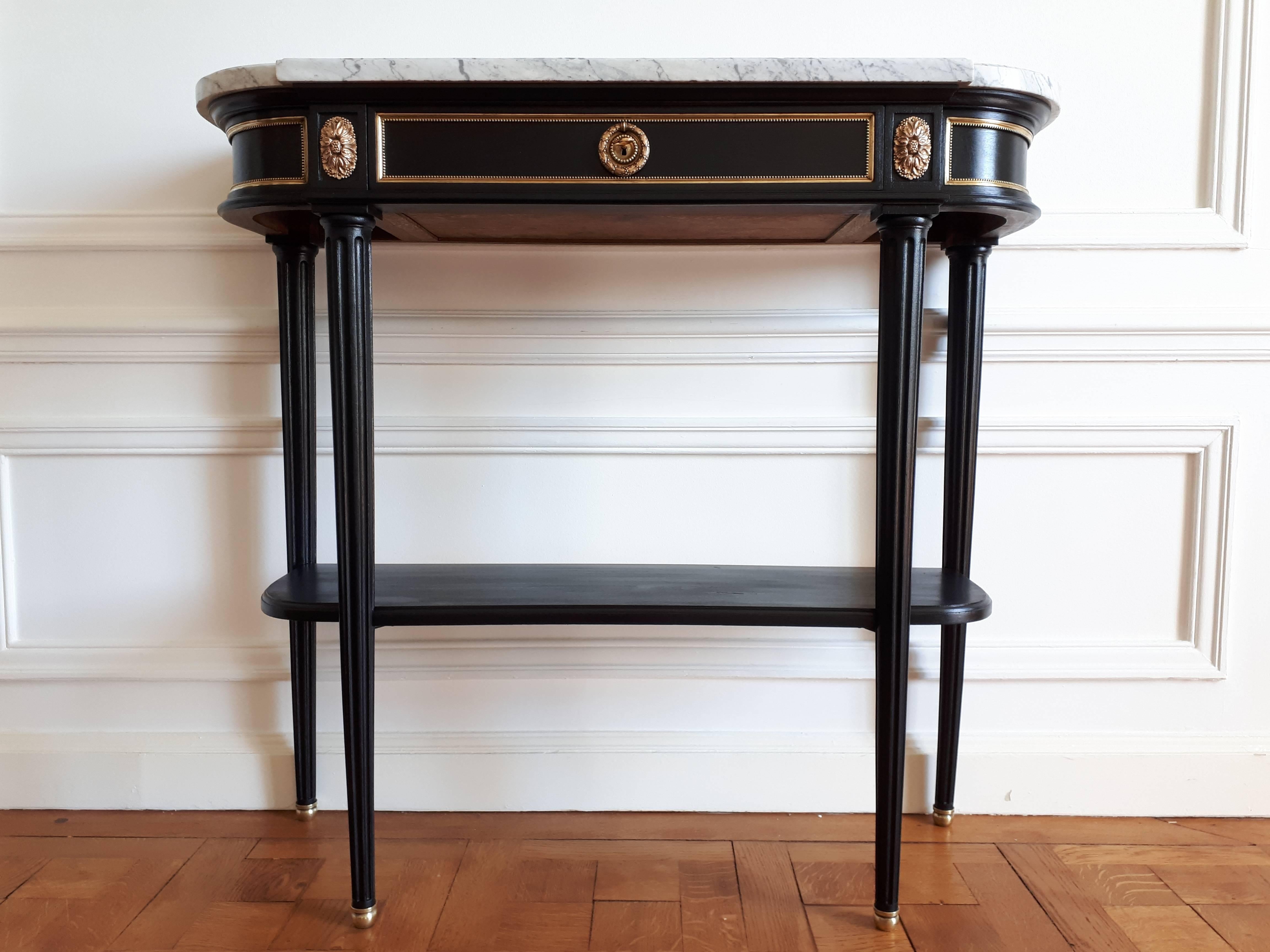 Antique console Louis XVI Style, topped with a white and grey marble Carrara.
The four feet are fluted and finished with golden bronze clogs.
On the upper belt there are four gilt bronze pieces typical of the Louis XVI style, and a dovetailed