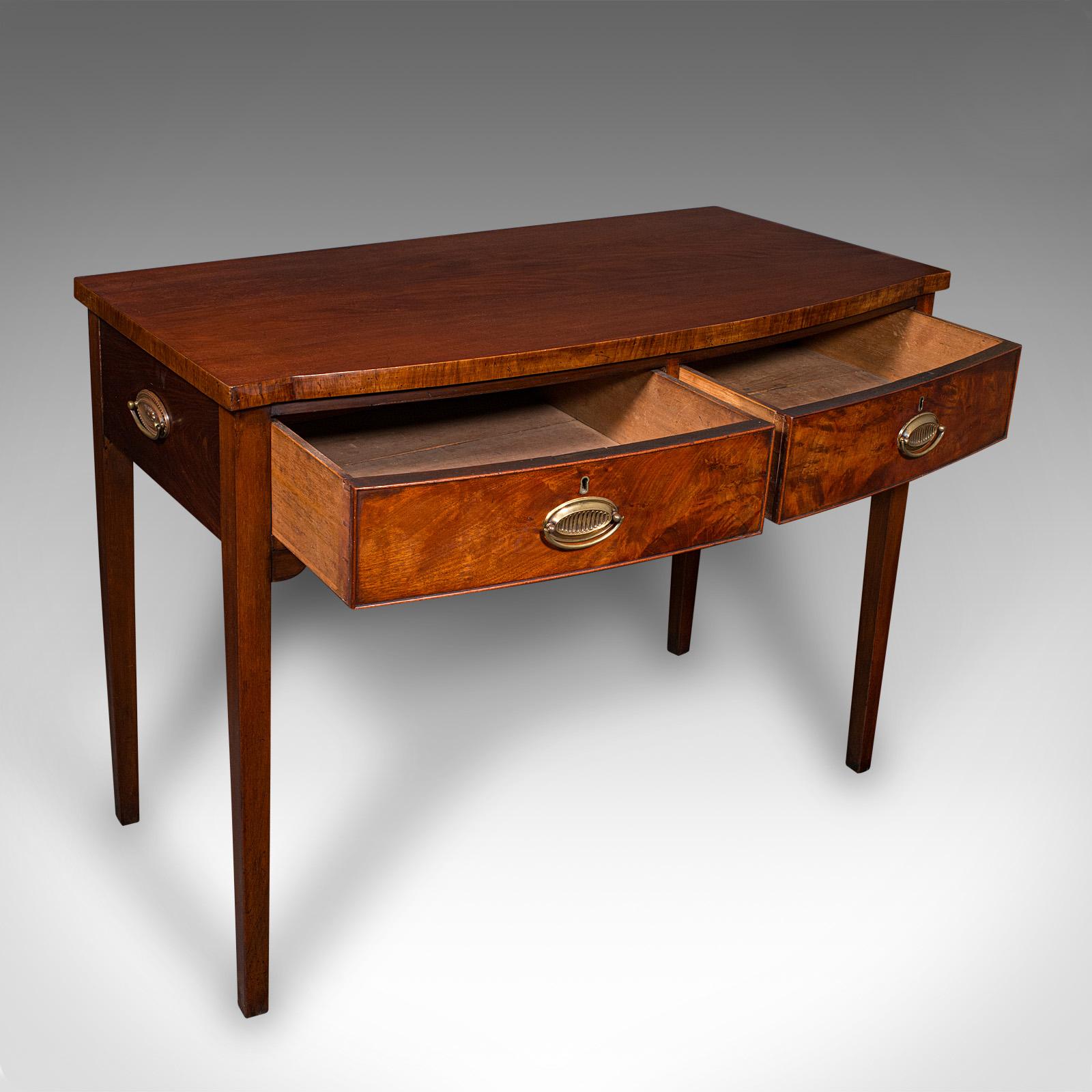 This is a fine antique console writing desk. An English, mahogany two drawer side table, dating to the Georgian period, circa 1800. Presenting superb craftsmanship, this desk offers elegant proportion and refined decorative appeal.

Appealing bow