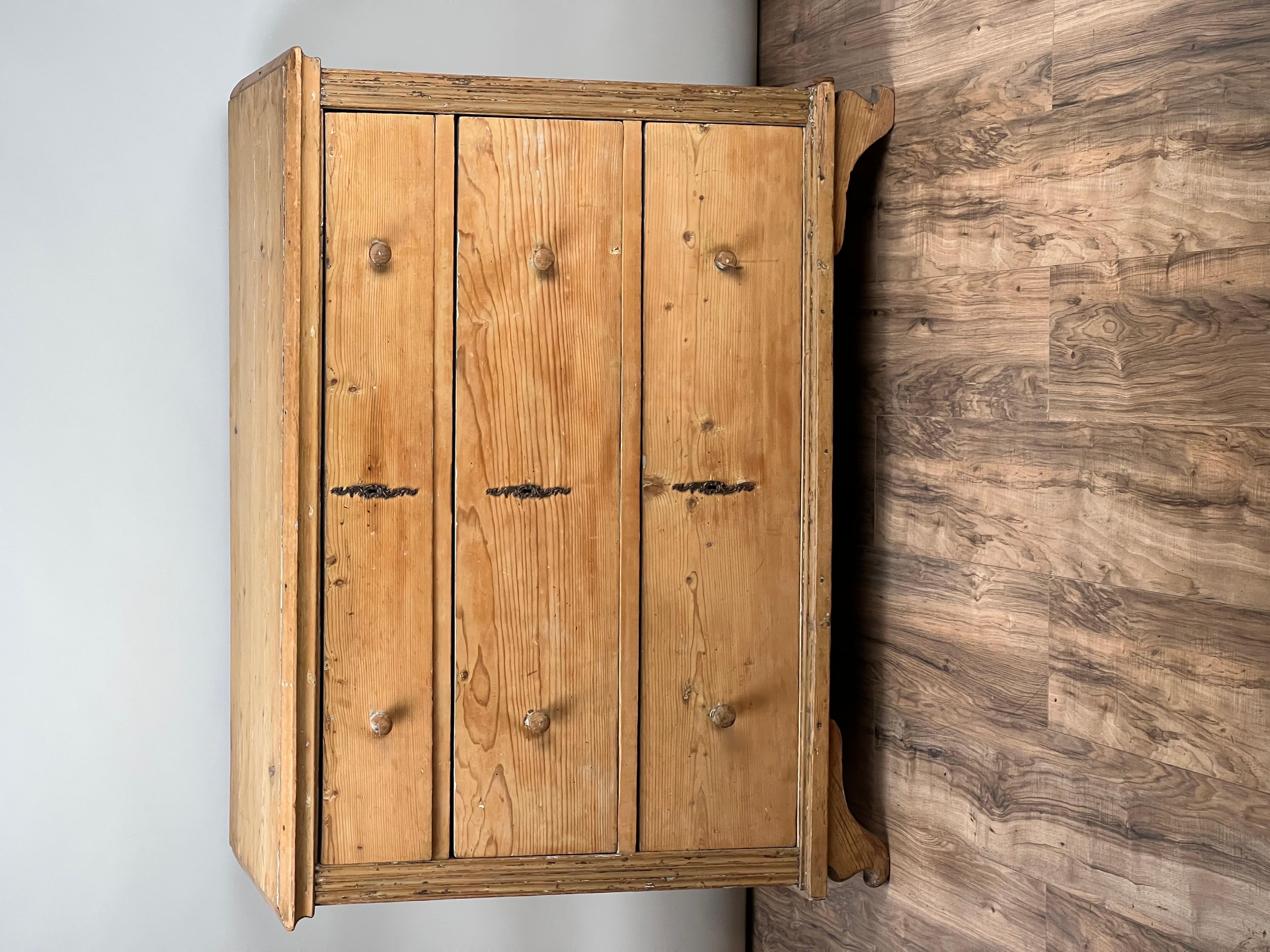 This Antique Continental Biedermeier Pine Three Drawer Chest, c. Early 19th Century, offers a striking example of rustic simplicity with its raw, unfinished pine. The piece has clearly been cherished for its natural beauty, with the previous owner