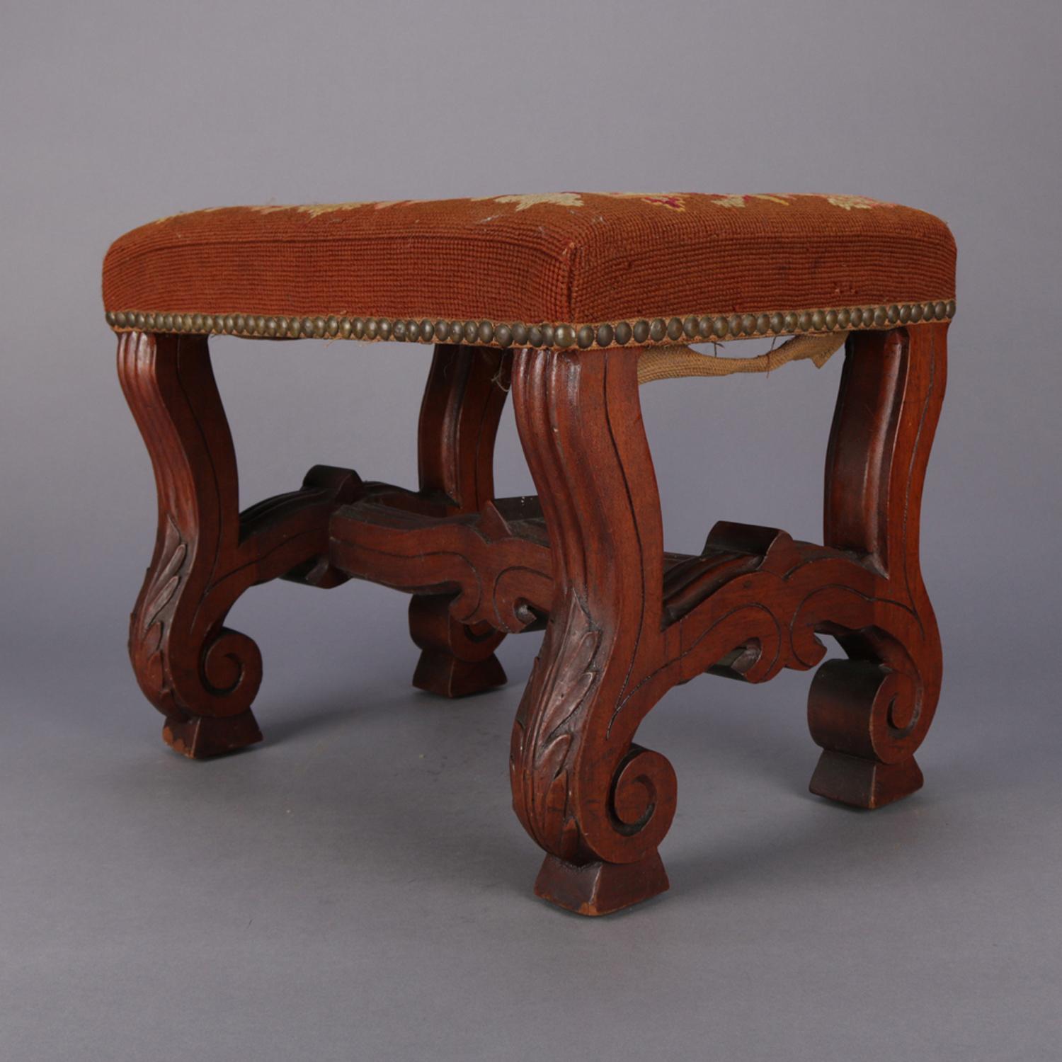 An antique Continental footstool having walnut base in trestle form with incised banding and carved acanthus scroll feet supporting tapestry needlepoint cushion with bird and foliate design, circa 1850

Measures: 12