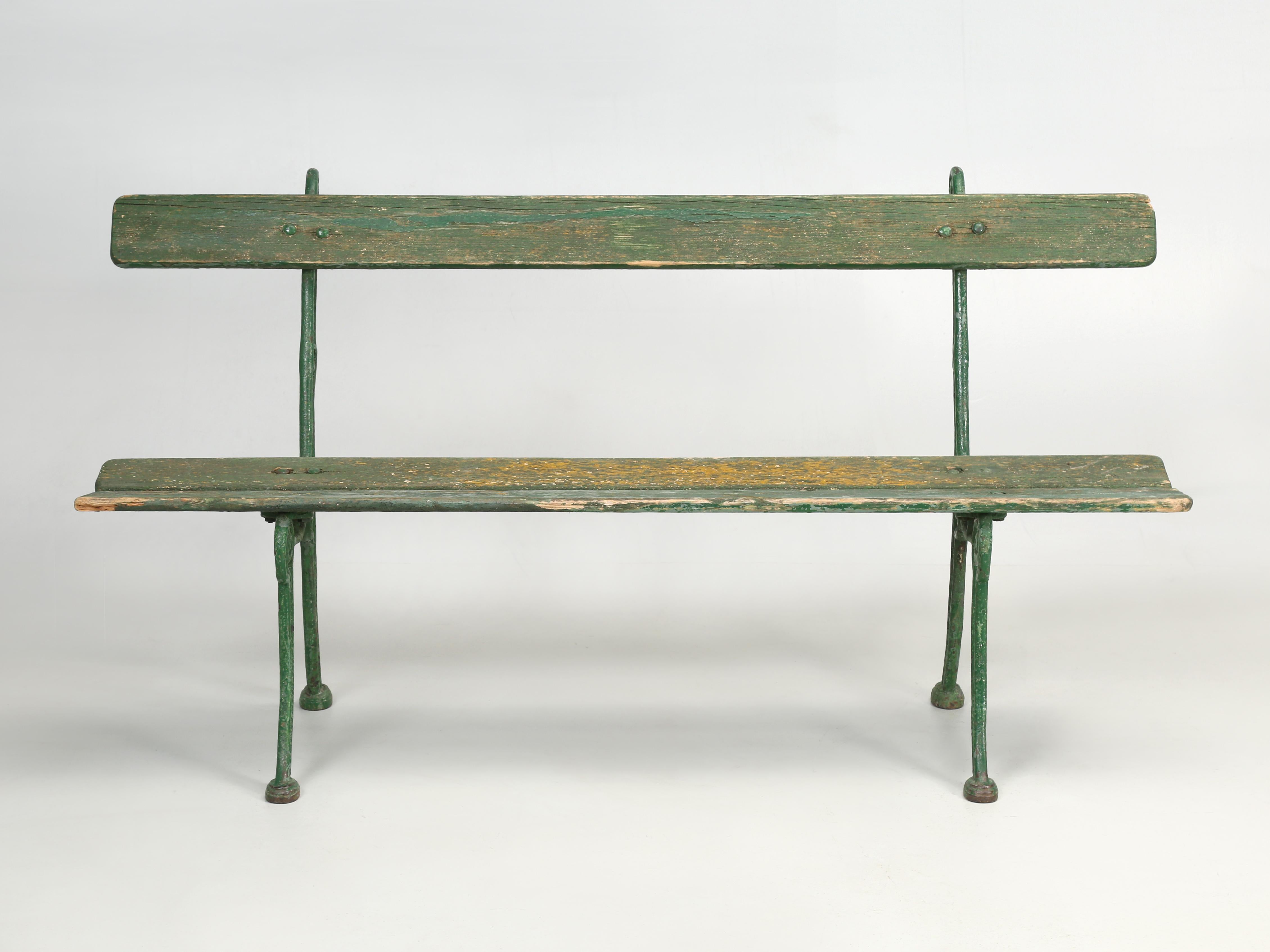 Antique European garden bench in old green paint. The cast iron frame is an unusual design with exceptional details. The paint is perfect for those who appreciate old paint, but rather easy to correct if that's not your taste. 
**Height provided