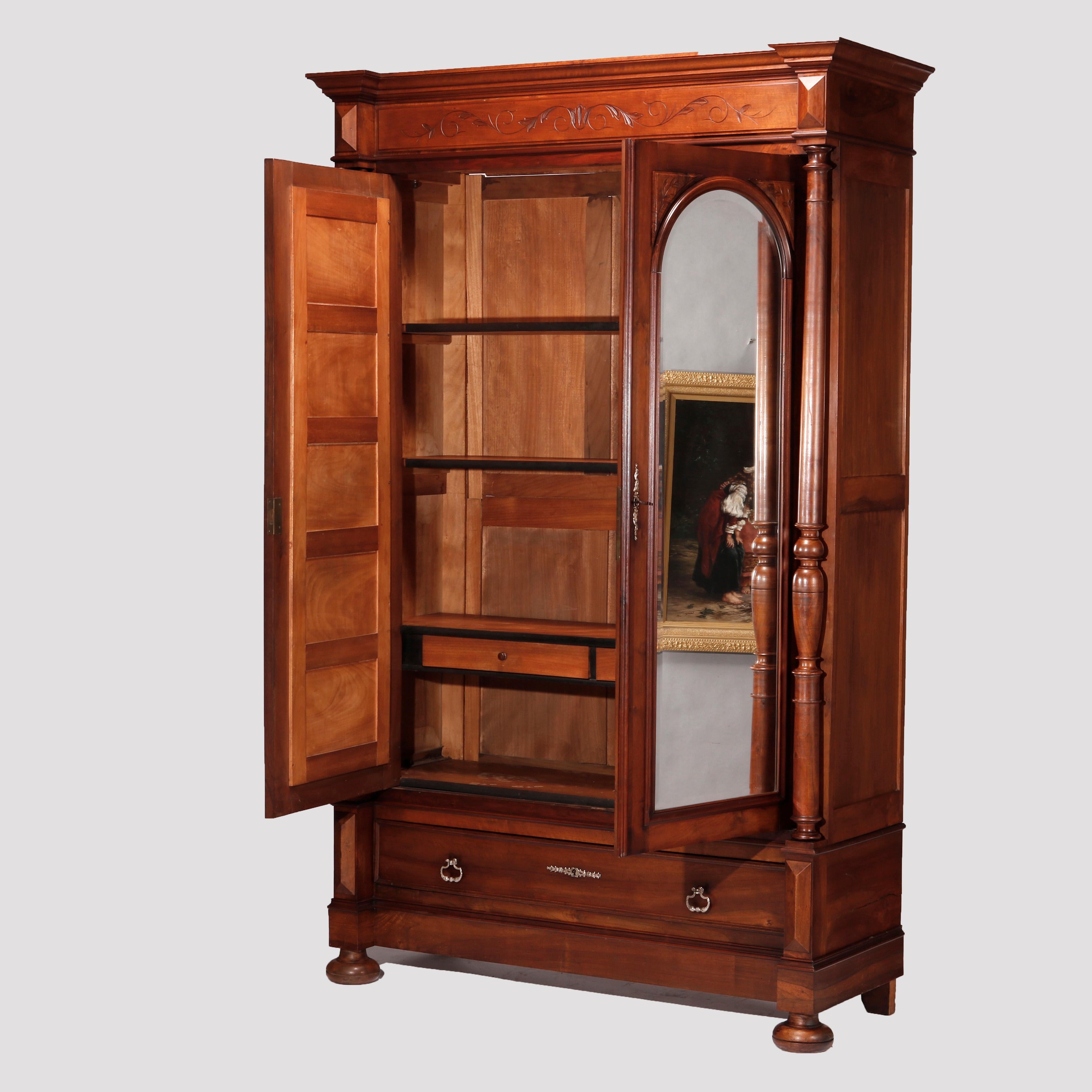 An antique Continental wardrobe offers walnut construction with double doors having arched mirrors and flanking turned column supports over single lower drawer raised on bun feet, c1890

Measures - 90.5''H X 59''W X 21''D.