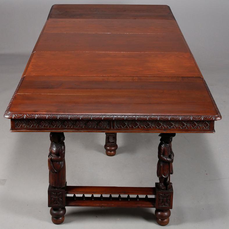 An antique Continental extension dining table offers oak construction with carved foliate skirt surmounting base having sculptured figural legs, accommodates three 18