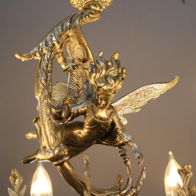 An antique Continental figural chandelier offers cast and silver gilt frame with sculptural angel over scroll, drape and foliate form base having six scroll form arms terminating in double candle lights, c1930.

Measures: 25