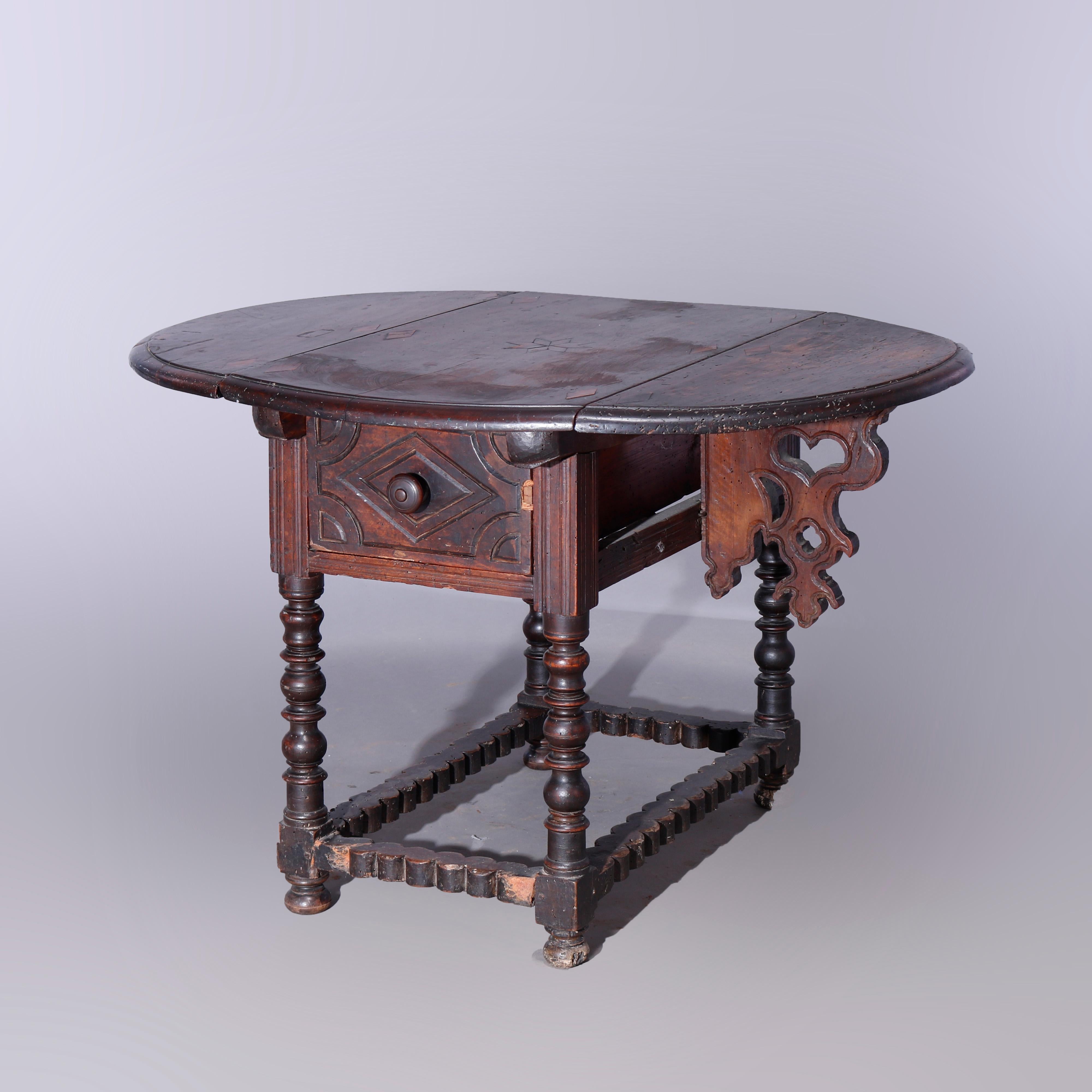 An antique Continental drop leaf table offers walnut construction with beveled drop leaf top having inlaid stylized floral and diamond design over single drawer, raised on turned balustrade legs with shaped and scroll form leaf supports, 17th