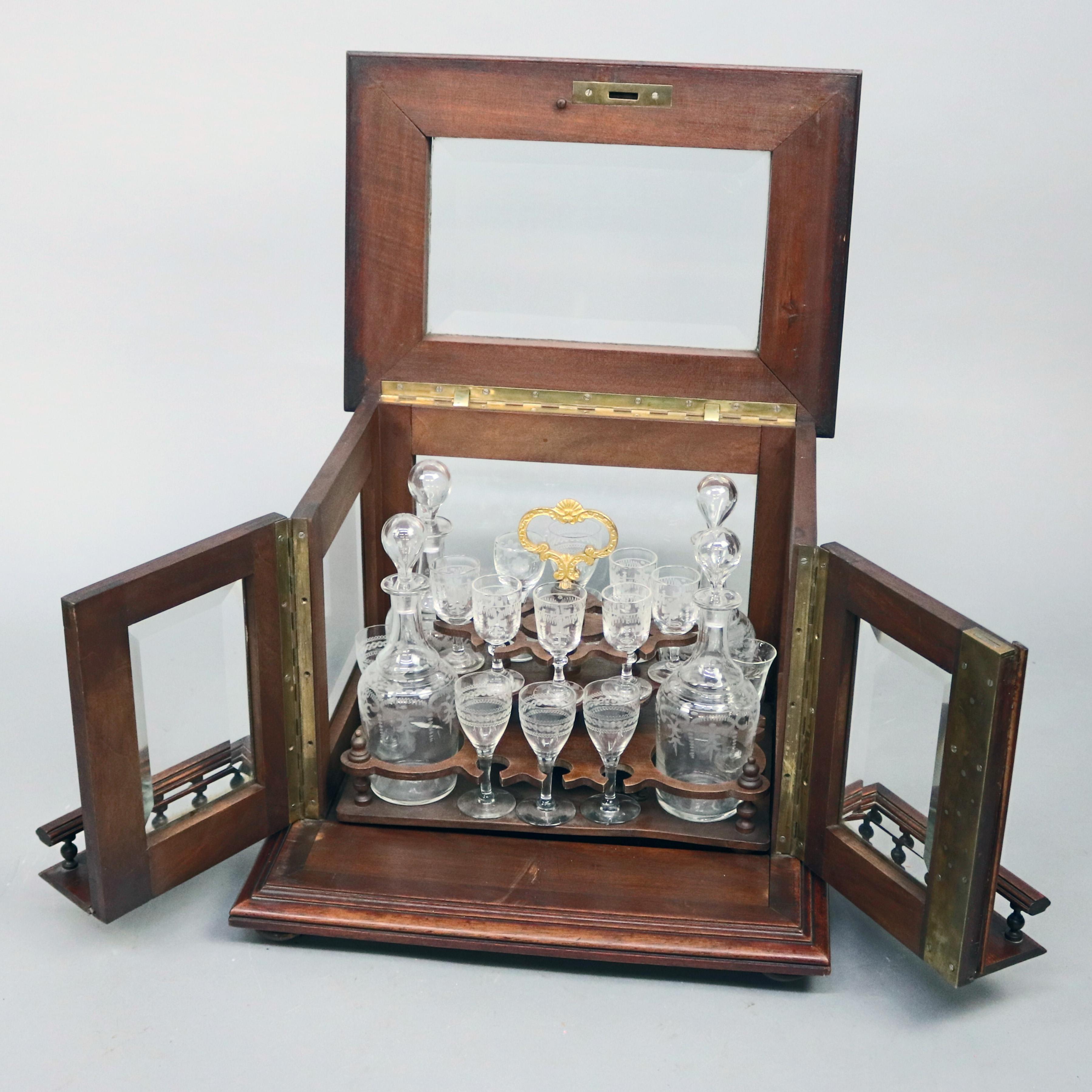 An antique continental Tantalus set offers glass case having mahogany frame and double doors opening to reveal mahogany tray with gilt handle and housing etched glass decanters and stemware, circa 1890

Measures: 12